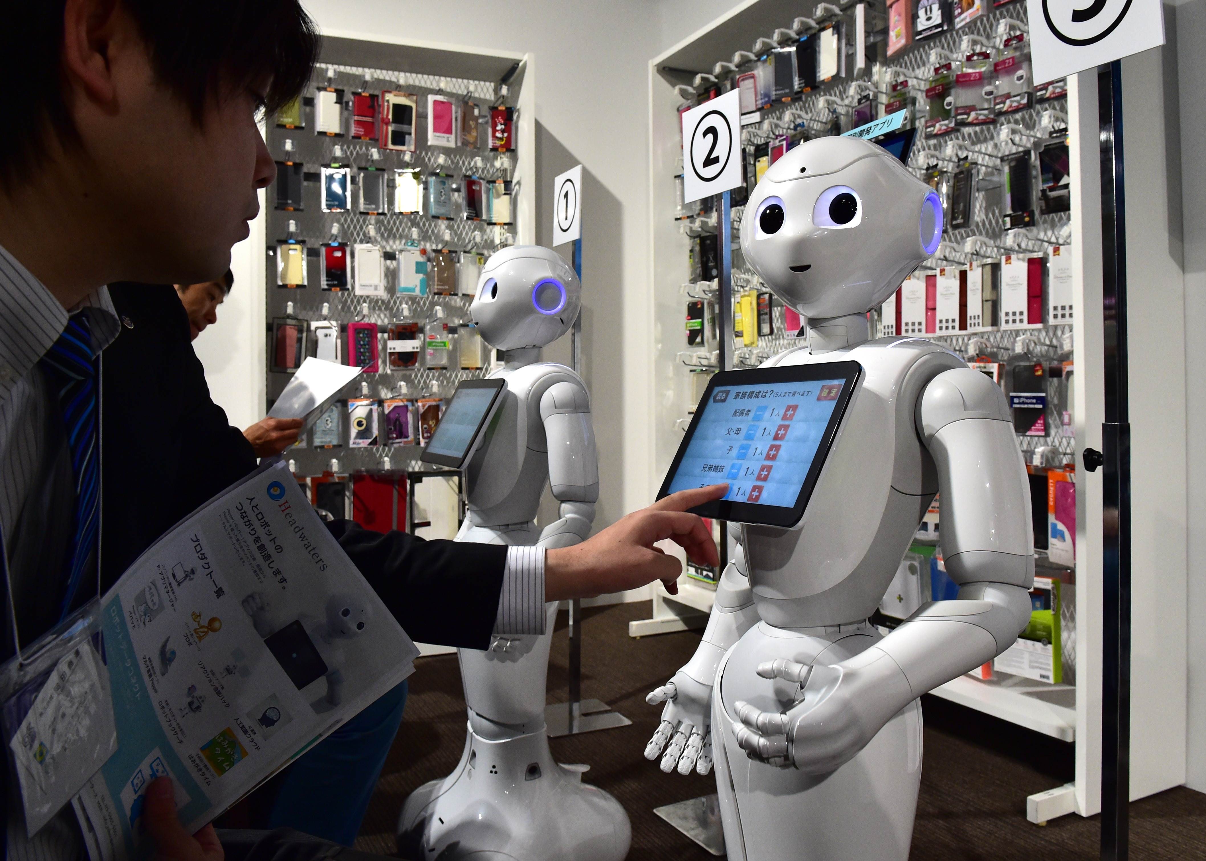 "Pepper", humanoid robots from Japan's telecommunication giant Softbank, are displayed at a smartphone stall to illustrate their applications for corporate use at the "Pepper World" exhibition in Tokyo on January 28, 2016. Softbank announced the company will open a pop-up smartphone shop in Tokyo next month as five Peppers will sell the smartphones to display their skills for customer services. AFP PHOTO / Yoshikazu TSUNO