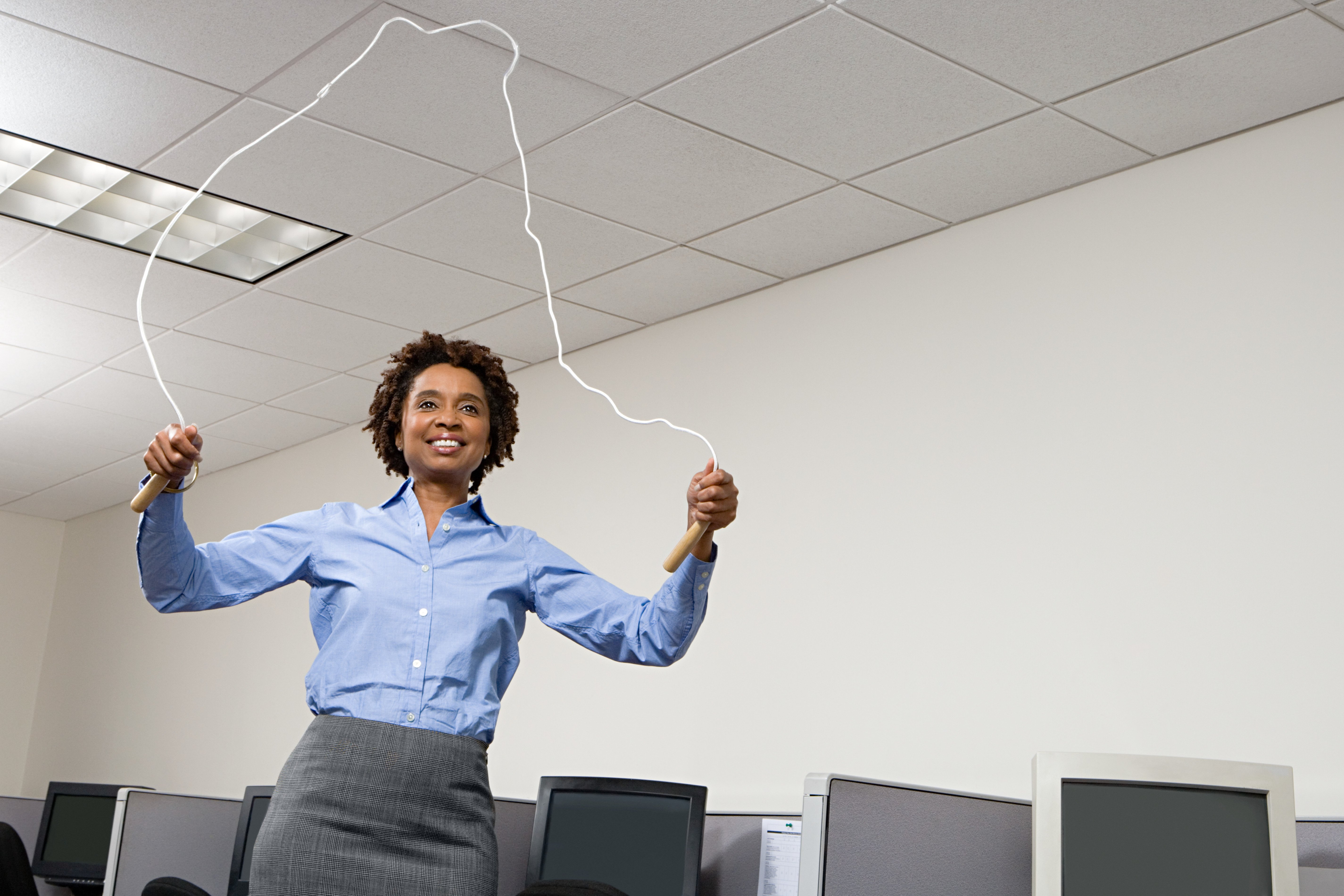 Woman skipping in office --- Image by © Image Source/Corbis [15FEBRUARY2016 POSTURE]