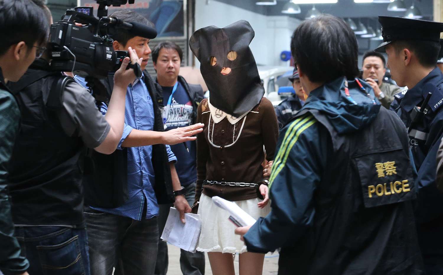 The suspect was hooded and handcuffed when she got out of an unmarked police car and was escorted into the building at 3.10pm. Photo: Felix Wong
