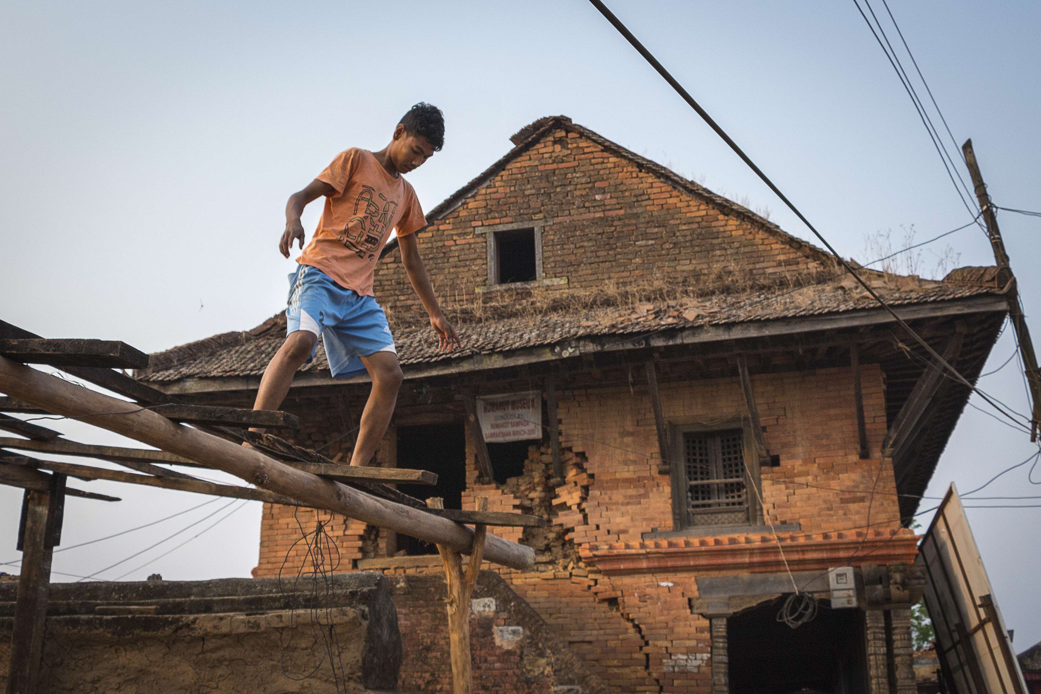A boy works on the roof frame of a building next to the quake-damaged Bhairavi temple in the historic village of Nuwakot, Nepal, a year after the devastating April 2015 earthquake. Photos: Tessa Chan