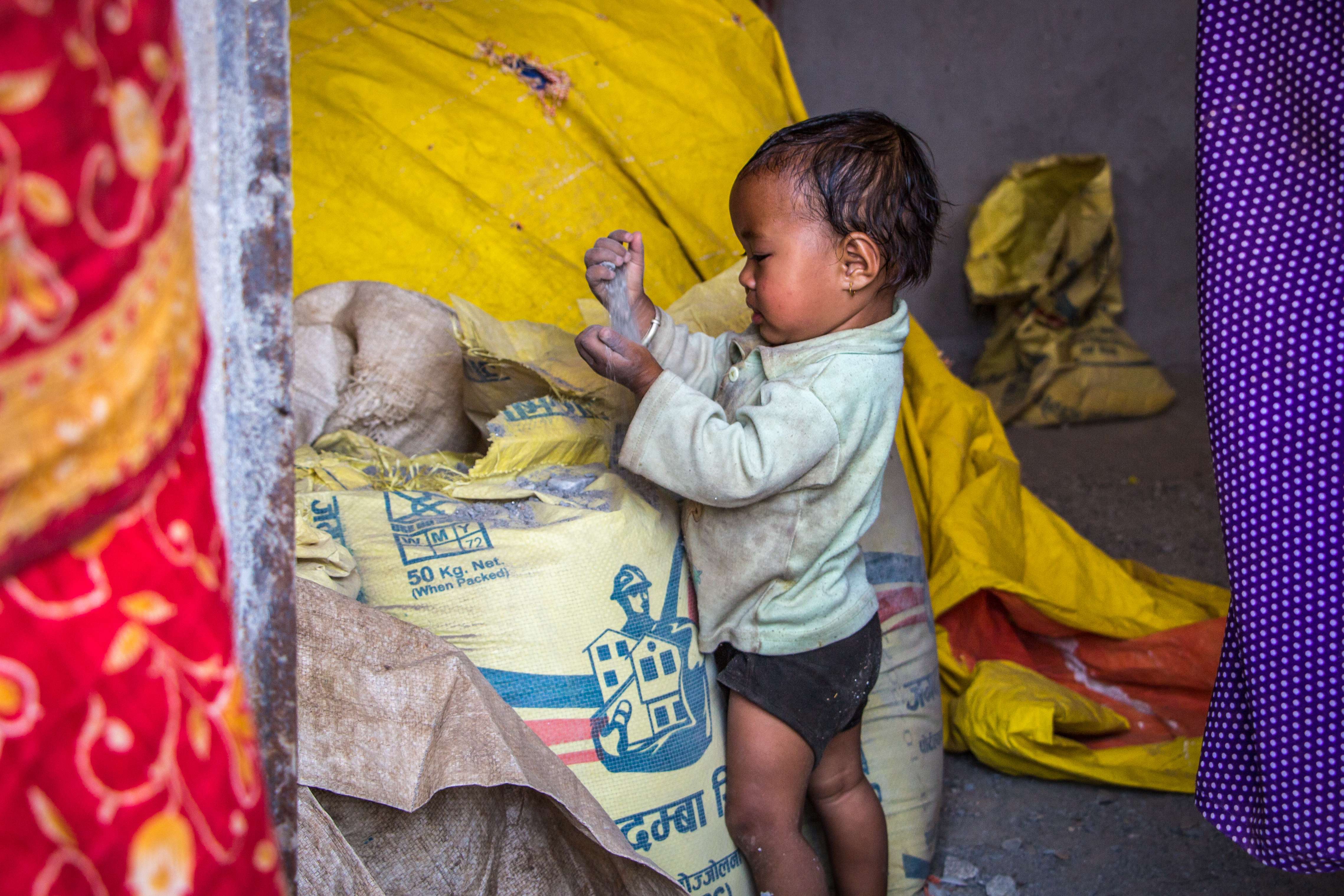 A child plays with a bag of cement in a new family home built with the help of All Hands Volunteers in Melamchi, Sindhupalchowk, Nepal. Photos: Tessa Chan