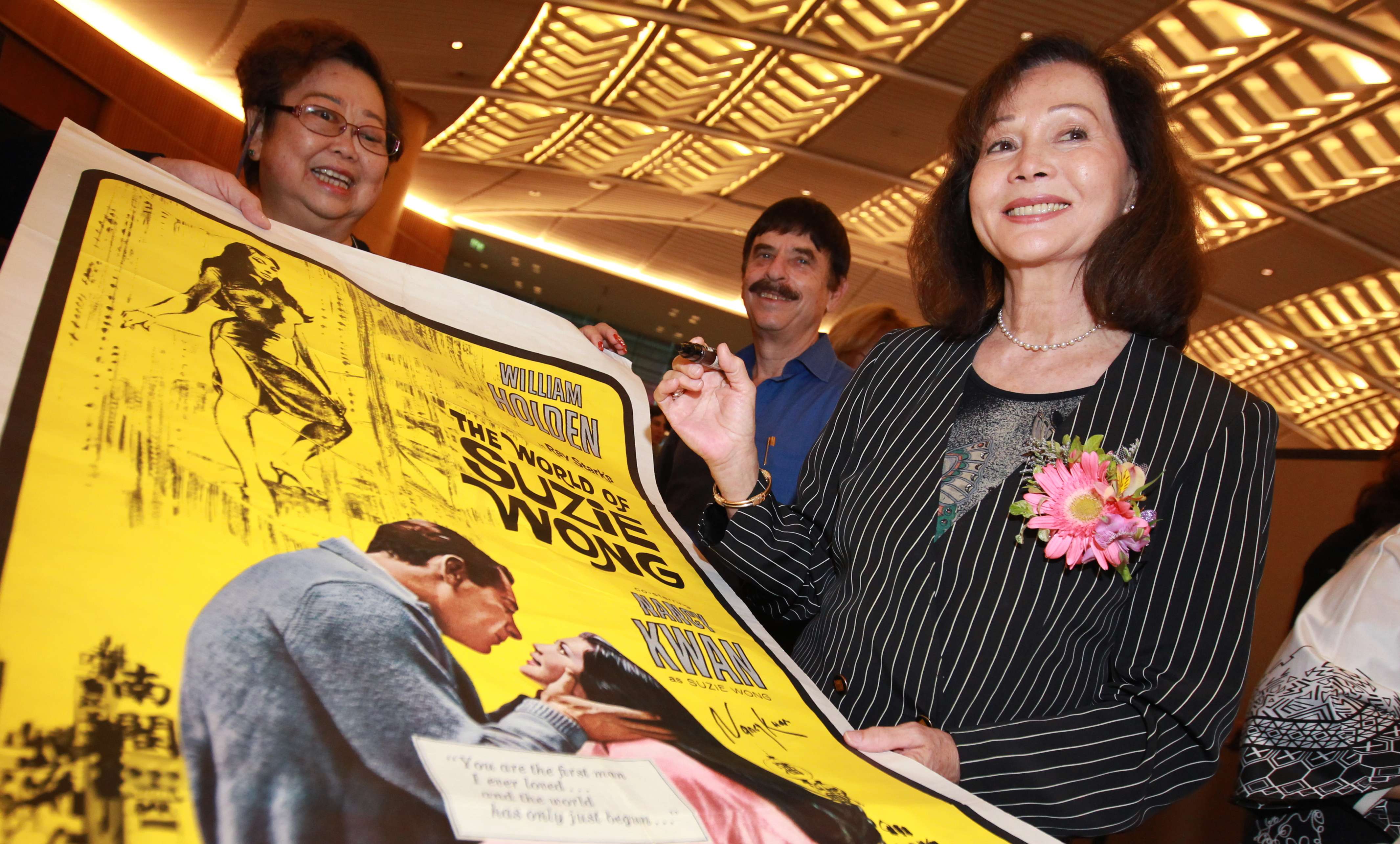 Nancy Kwan, star of the movie “The World of Suzie Wong”, signs a poster 50 years after the film’s release. Photo: Felix Wong