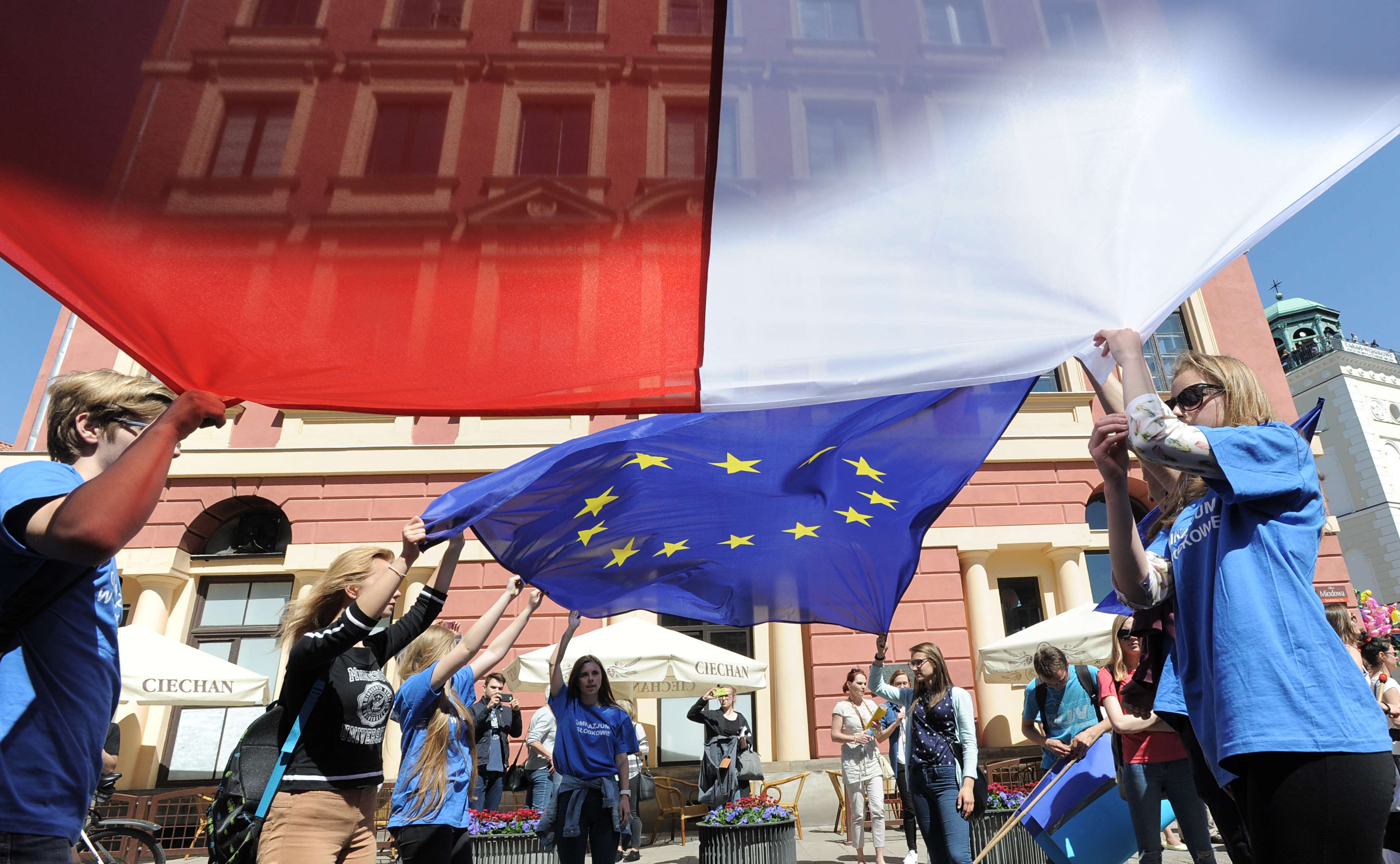 Young people in Warsaw wave the Polish and European Union flags during the yearly Schumann Parade supporting EU ideas. Photo: AP