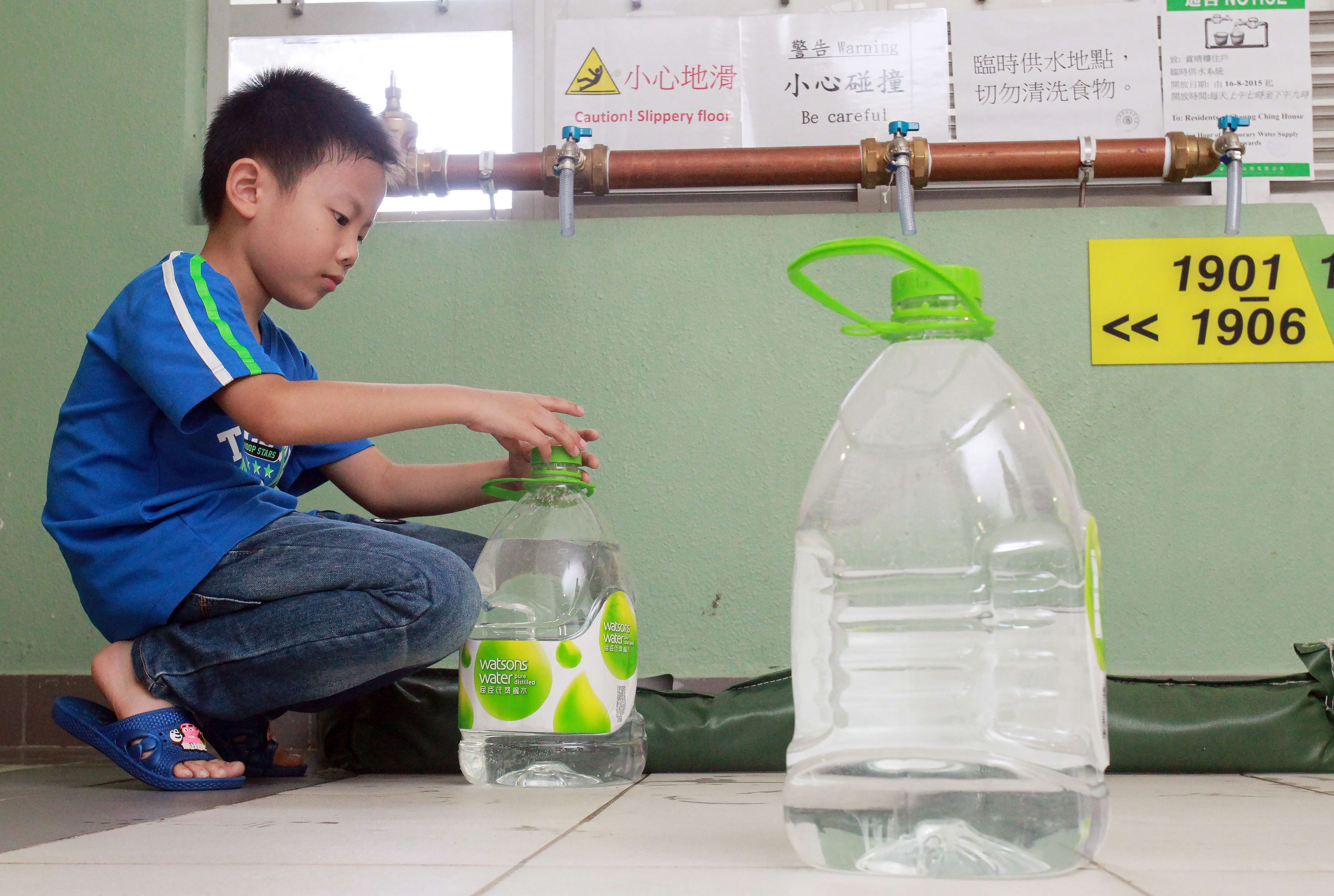 Edmond Ng Yat-long, 8, fetches water from temporary pipes on a floor at Sheung Ching House in Kai Ching Estate during the water scare last year. Photo: May Tse