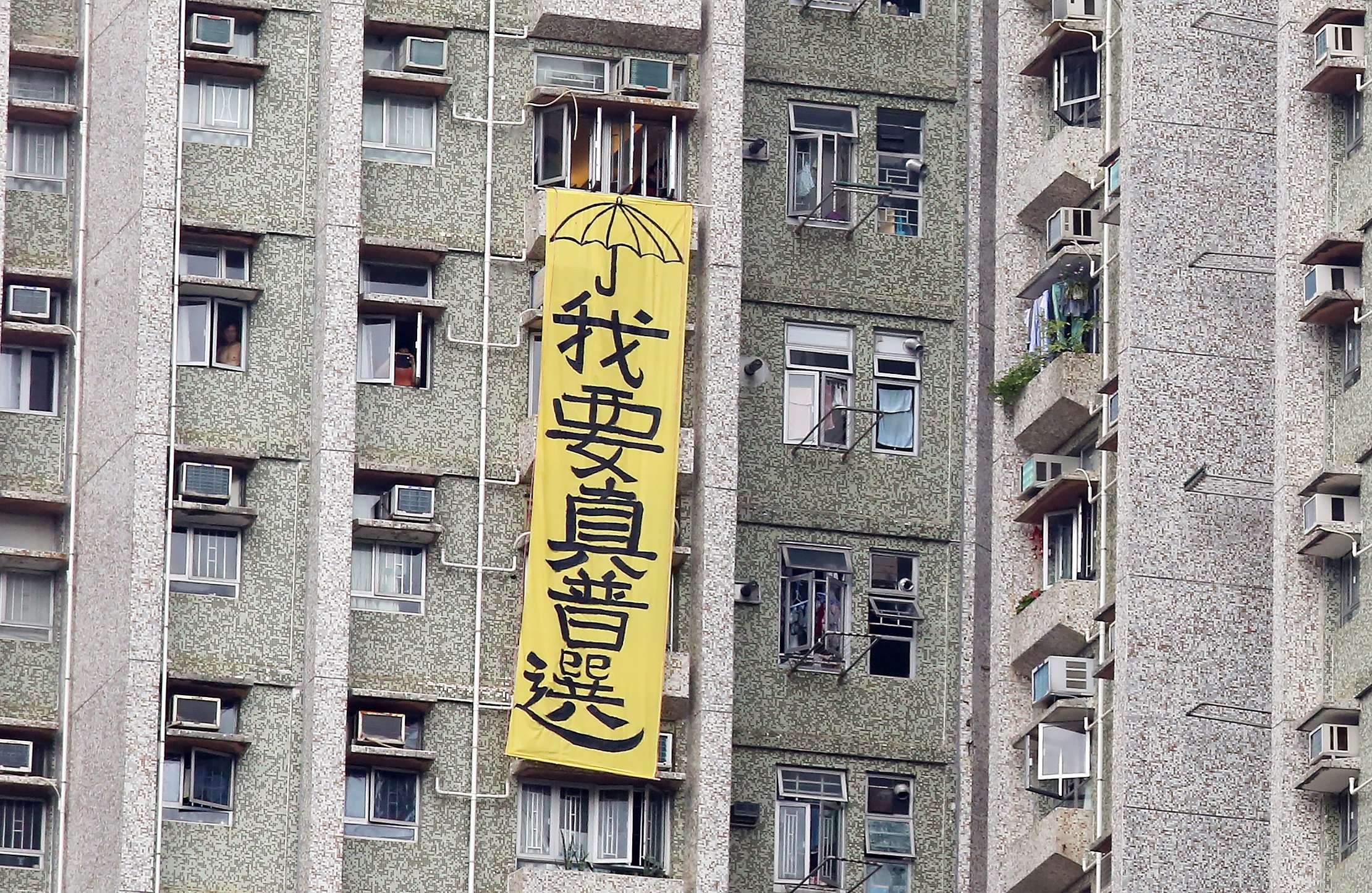A banner calling for genuine universal suffrage is draped outside a residential building next to a home for the elderly in Tseung Kwan O that Zhang Dejiang visited on Thursday. Photo: Nora Tam