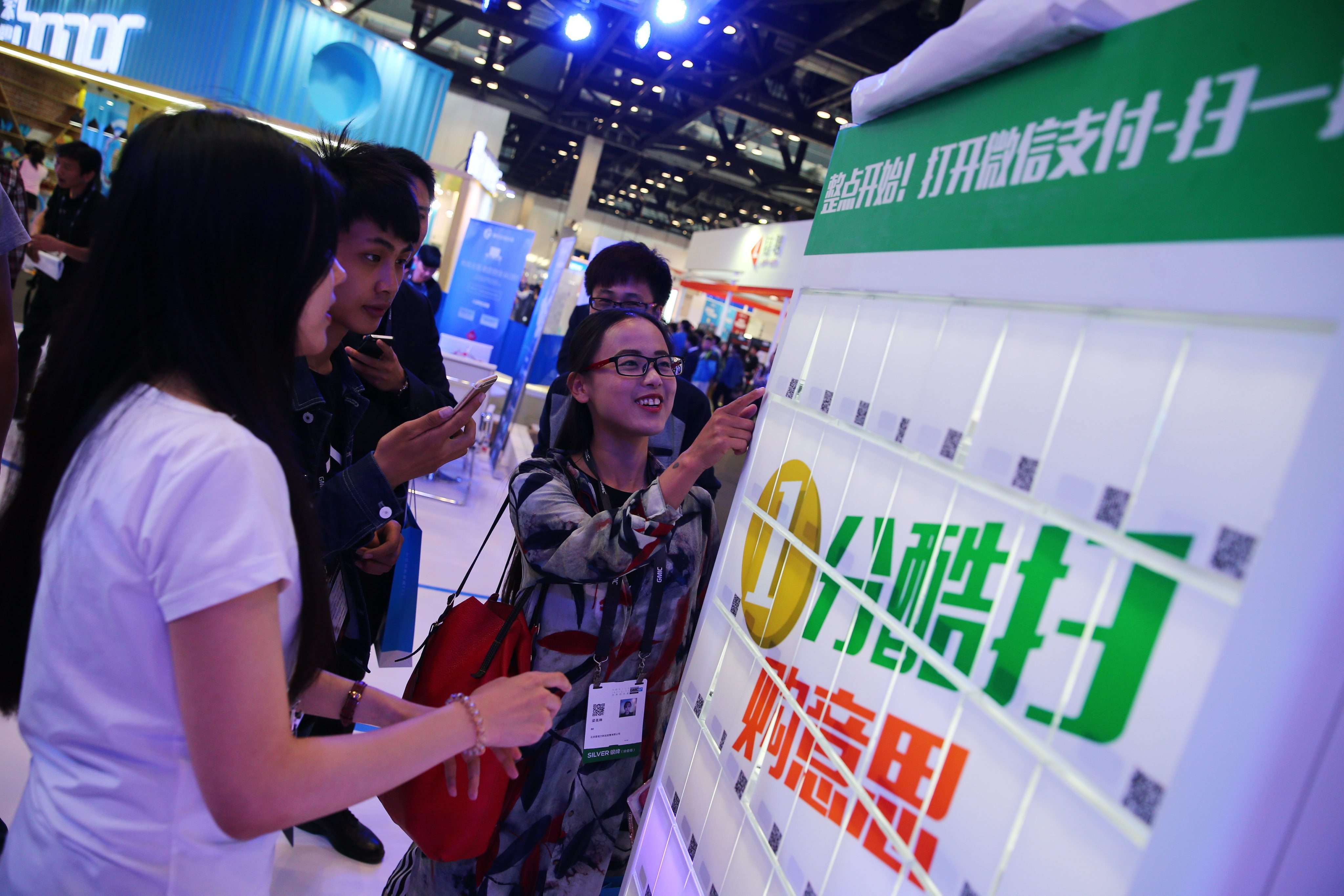 Visitors use the WeChat payment system for gifts at the 2016 Global Mobile Internet Conference in Beijing. Photo: EPA