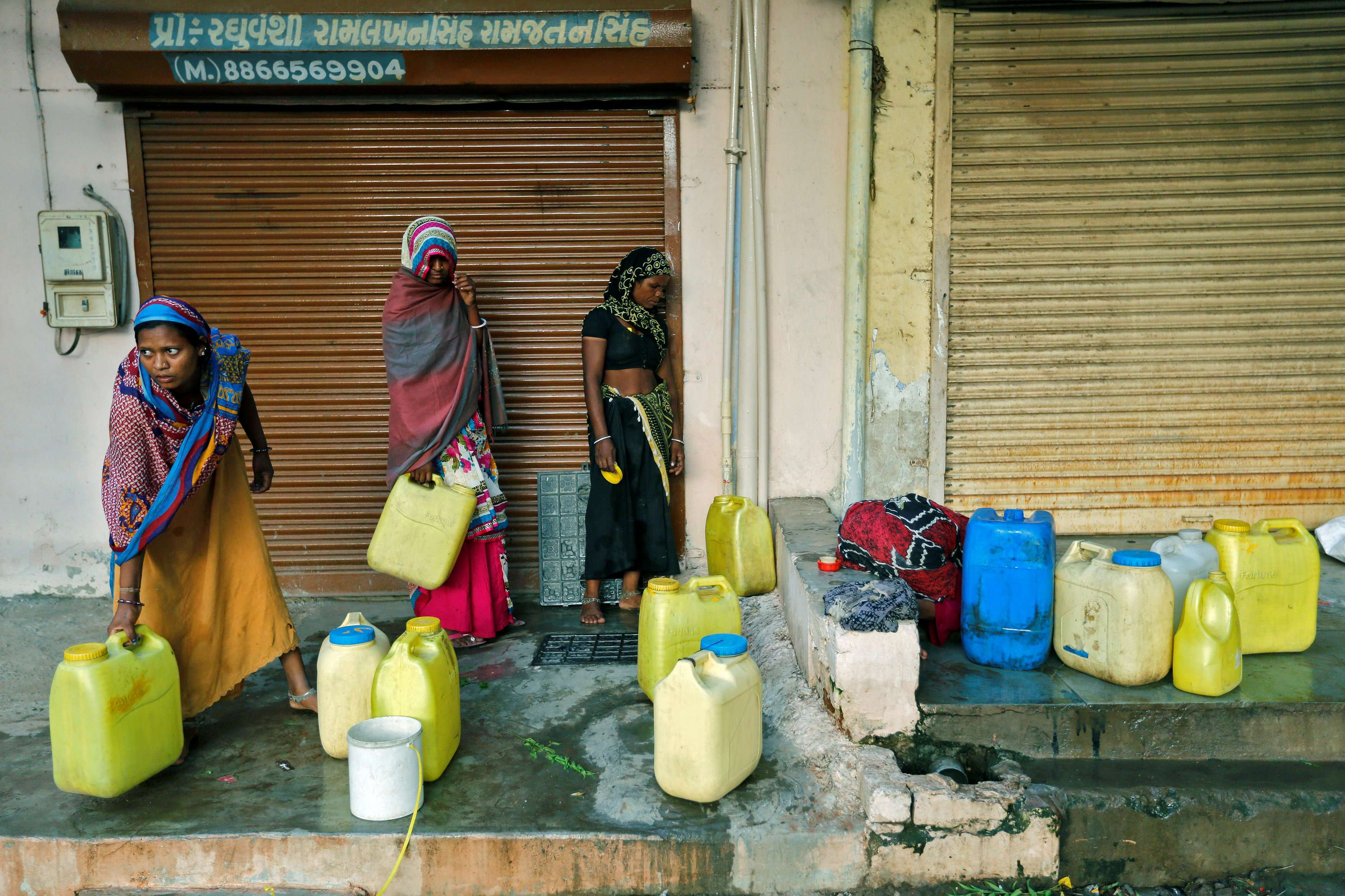 Women fill water containers from an underground tank on the outskirts of Ahmedabad, India. Improved access to sanitation, electricity, clean water supplies and transport reduces “time poverty” for women and girls, according to a study by the Asian Development Bank. Photo: Reuters