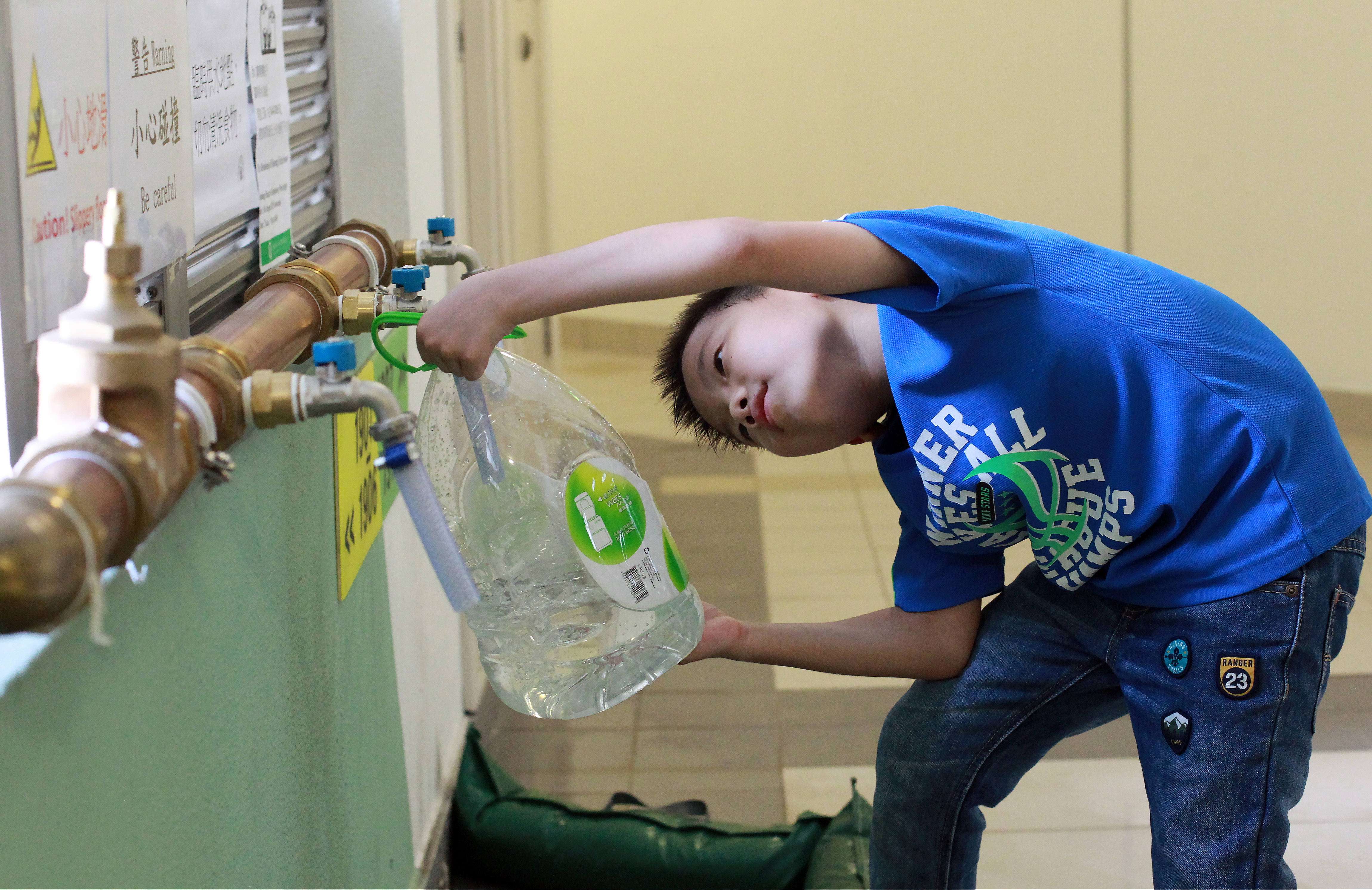 Edmond Ng Yat-long, eight, fetches water from temporary pipes in Kai Ching Estate. Photo: SCMP Pictures