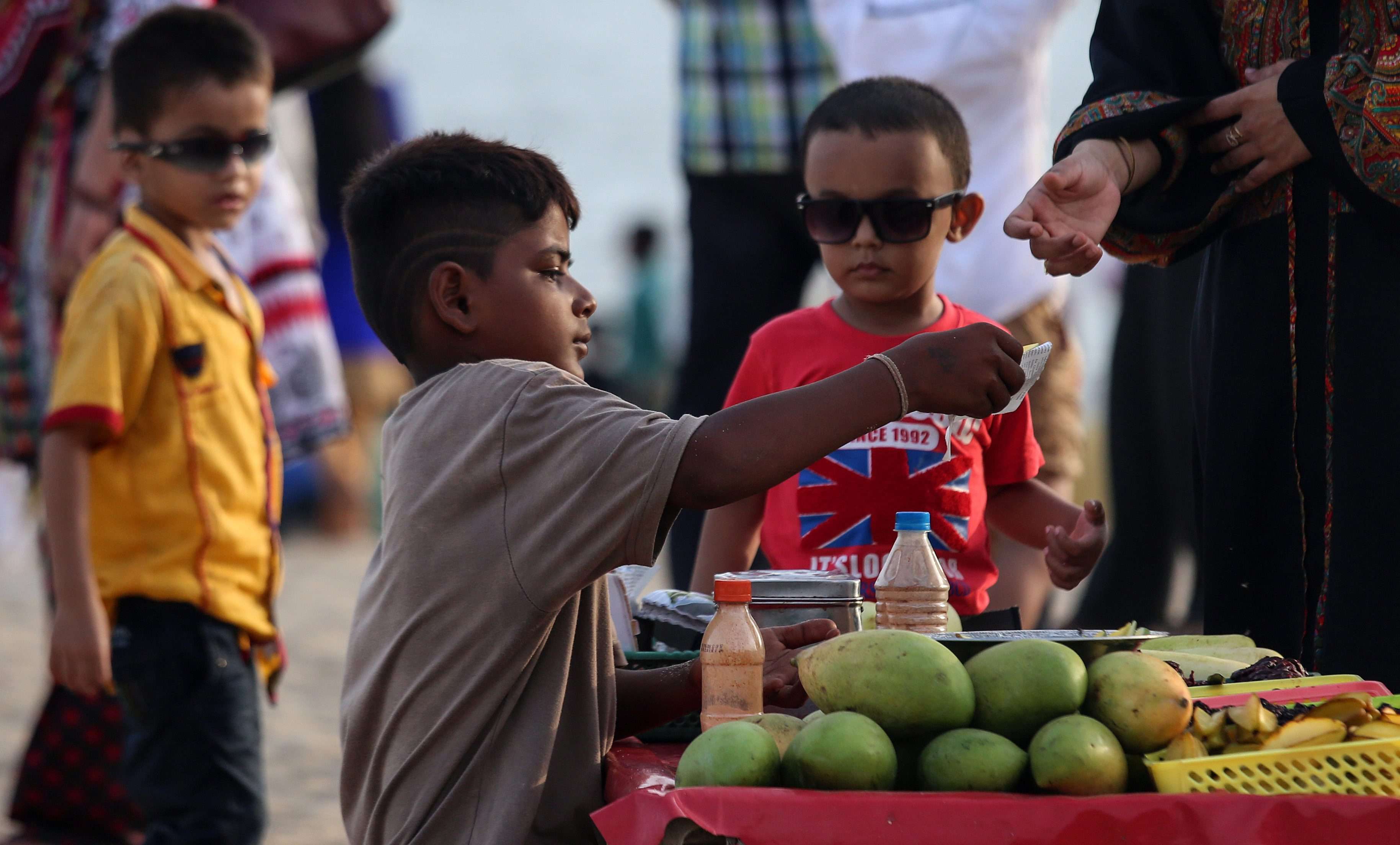 A boy sells mangoes at a beach in Mumbai, India. The Indian government has passed legislation to prohibit children between 14 and 18 years old from engaging in hazardous occupations. However, children under 14 are allowed to work in non-hazardous family enterprises and entertainment occupations. Photo: EPA