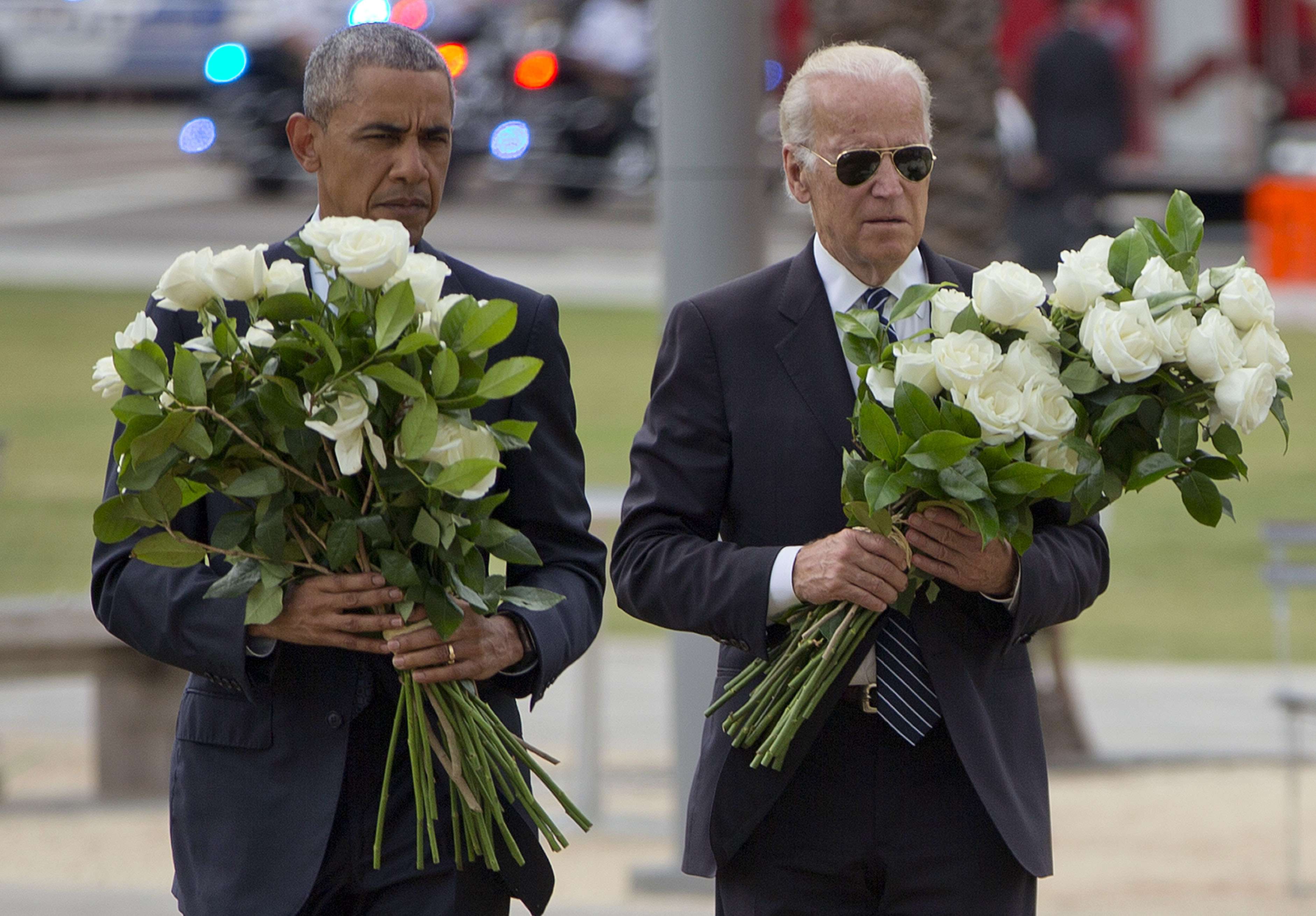US President Barack Obama with Vice-President Joe Biden carry bouquets comprised of a total of 49 white roses, one in honor of each of the deceased victims, as they visit a memorial to the victims of the Pulse nightclub shooting on Thursday in Orlando, Florida. Photo: AP