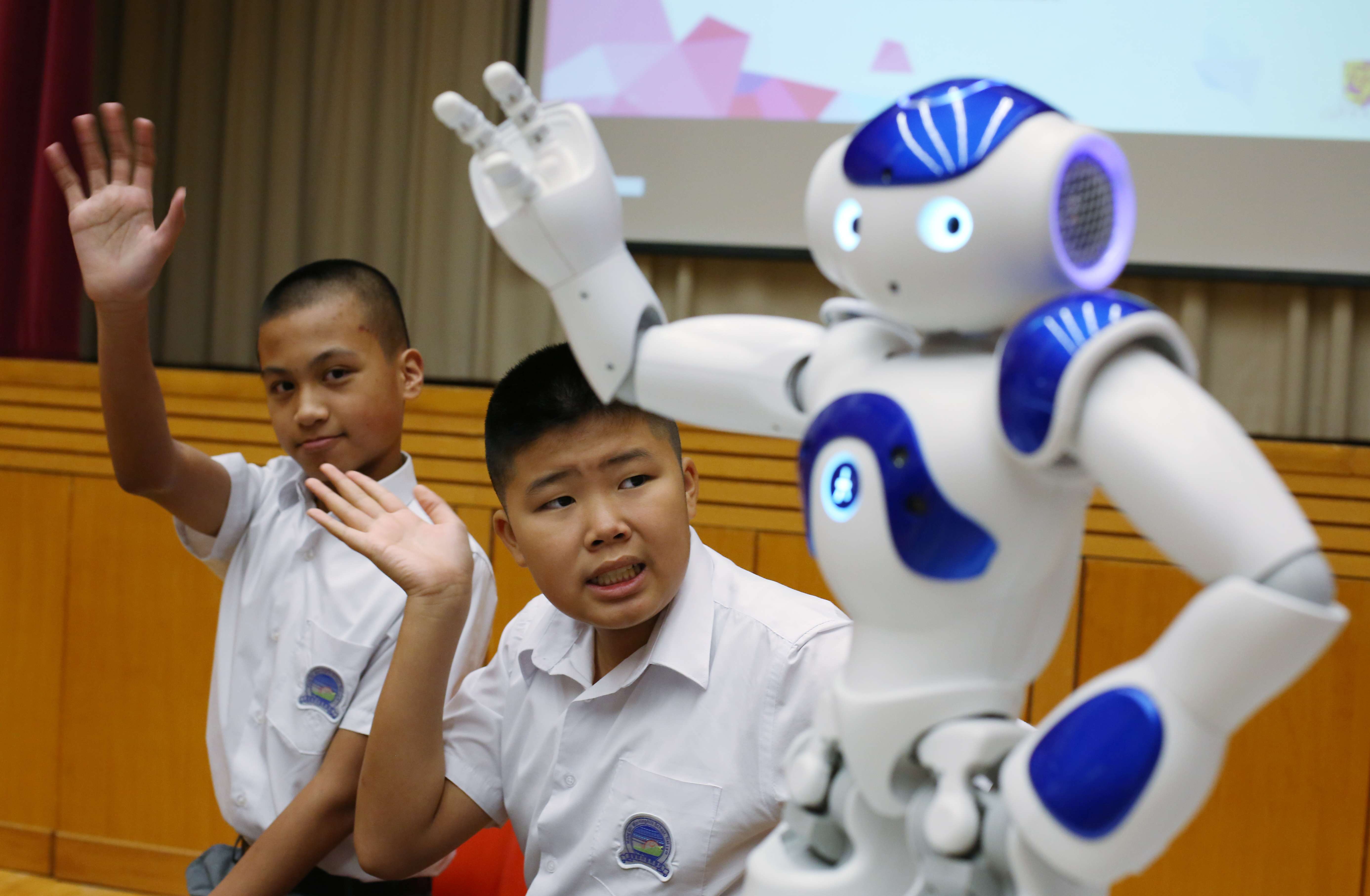 Lam Wai-lok (left) and Keung Hei-man with a ‘’social robot’’ that aims to improve the essential hand gestures of autistic children. Photo: Nora Tam