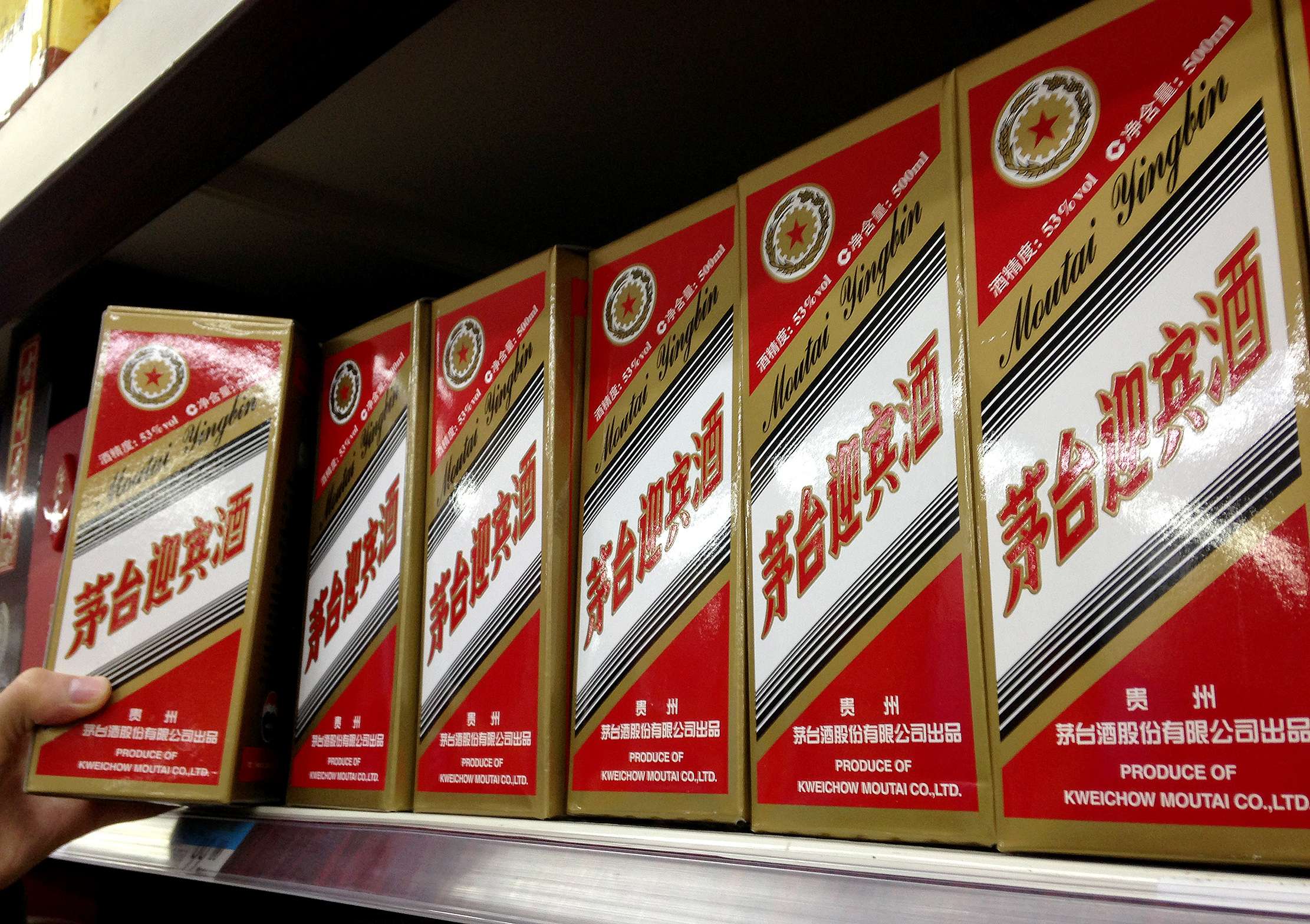 A man takes a bottle of mao-tai liquor from a supermarket shelf in Beijing. Photo: Xinhua