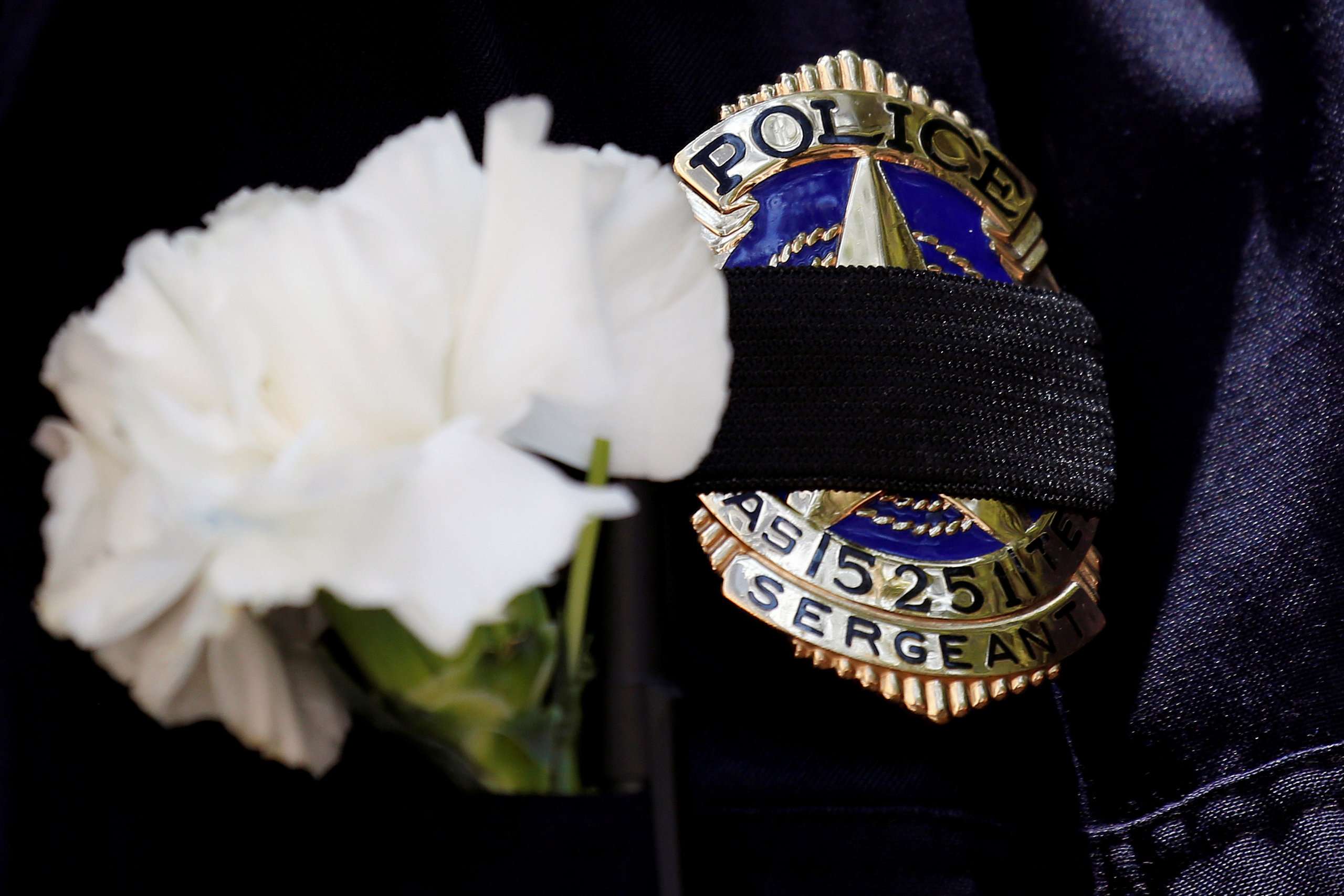 A Dallas police sergeant wears a mourning band and flower on his badge during a prayer vigil, one day after a lone gunman ambushed and killed five police officers at a protest decrying police shootings of black men, in Dallas, Texas, July 8, 2016. Photo: Reuters