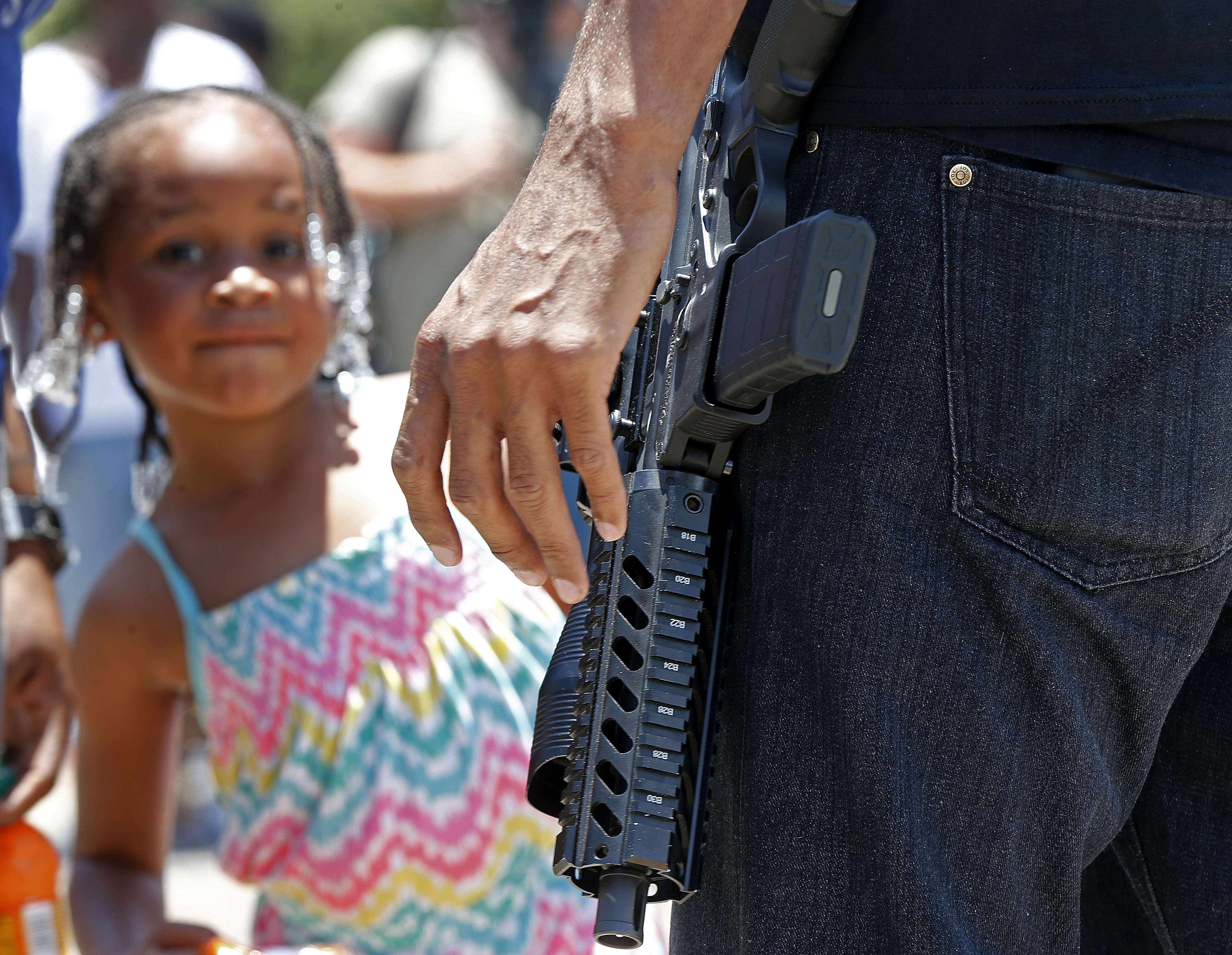 A child stands nearby as Jasiri Basel, an open carry advocate talks to reporters in front of the Triple S Food Mart in Baton Rouge, Louisiana, on Thursday. Photo: AP