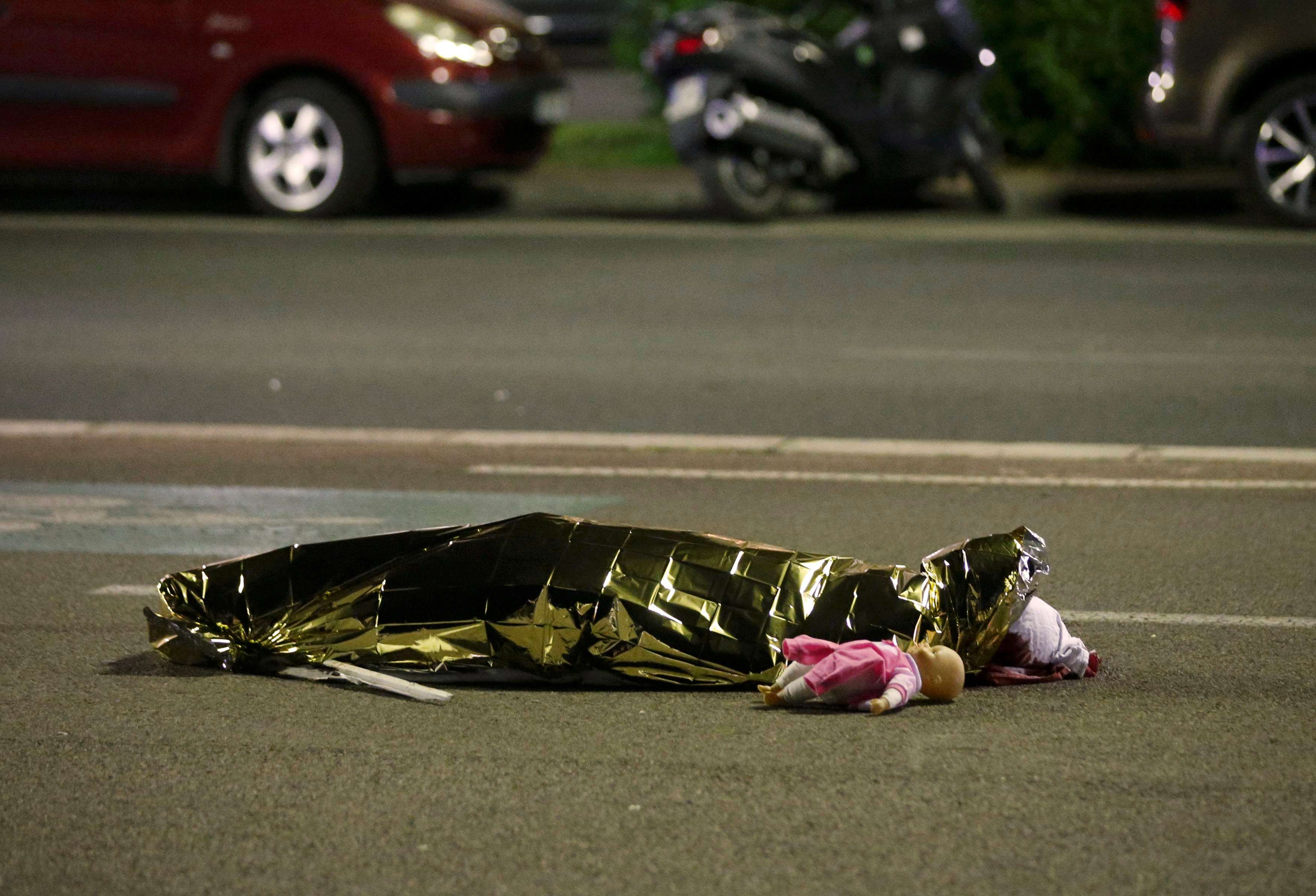 A body believed to be that of a child, a doll at their feet, is wrapped in a foil blanket on the Nice promenade in Thursday night. Photo: Reuters