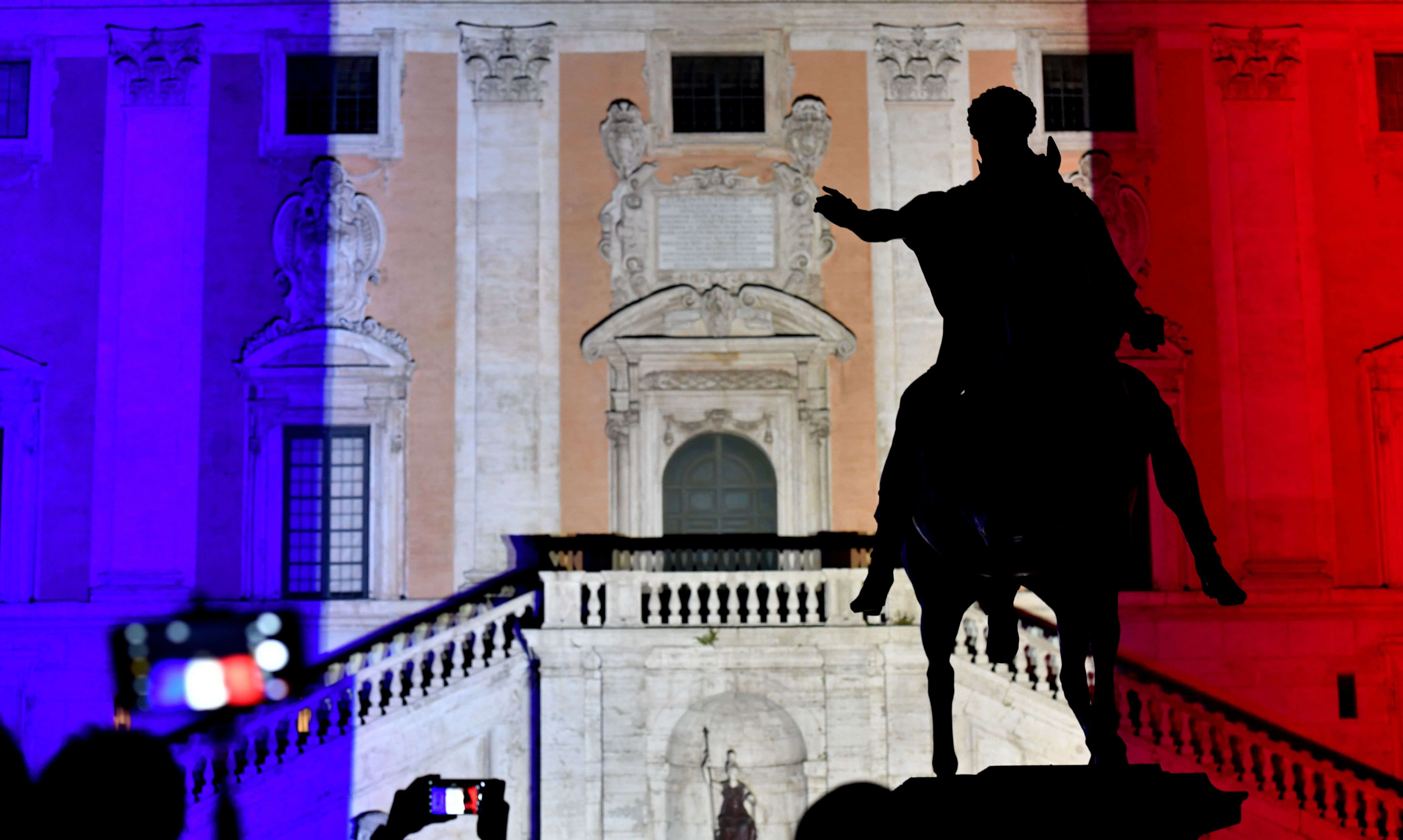 People take pictures as the colours of the French flag are projected on the Campidoglio in central Rome on July 15. Photo: AFP