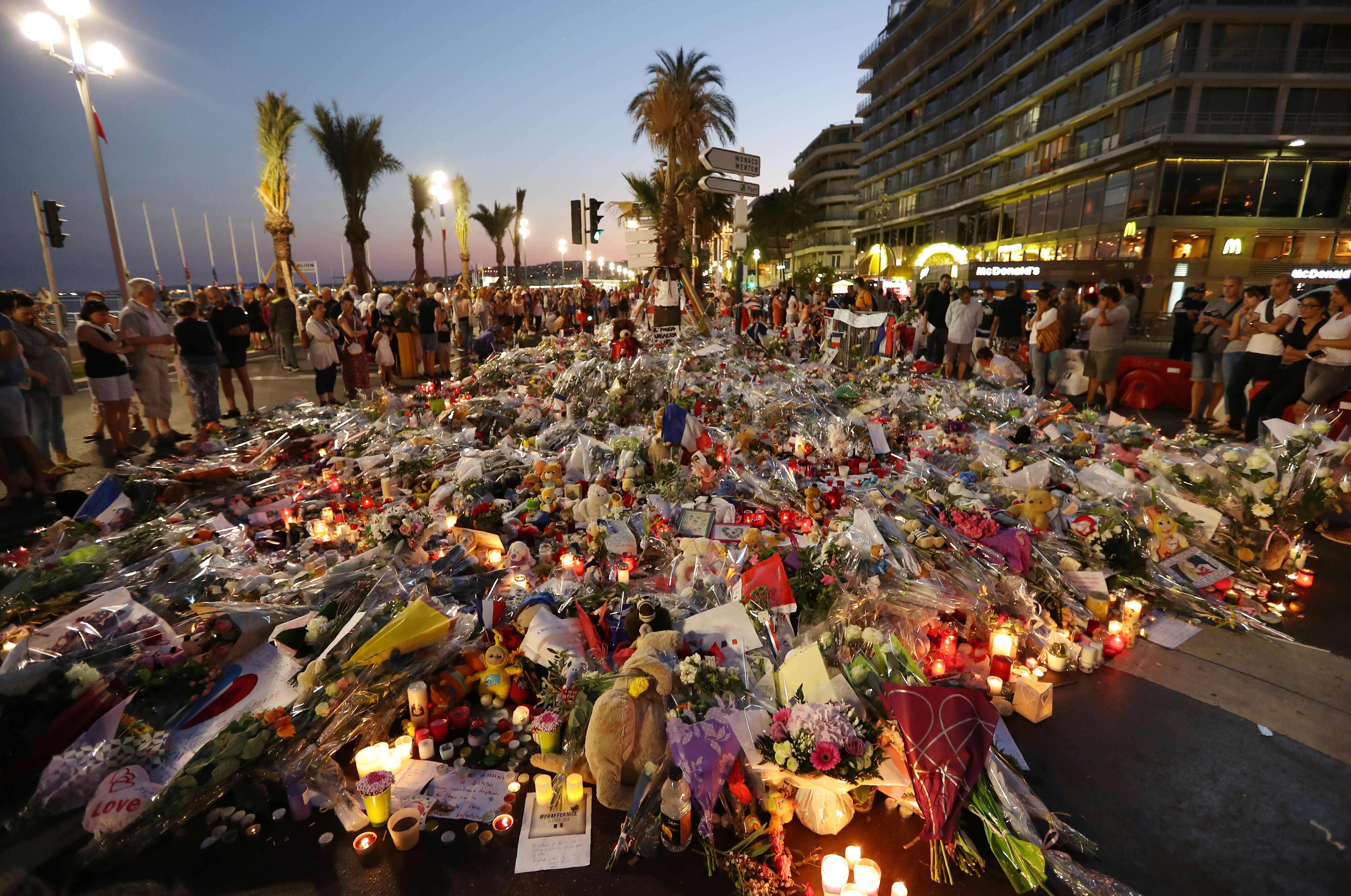 People stand in front of flowers, candles and messages laid at a makeshift memorial in Nice on Monday, in tribute to the victims of the deadly attack on the Promenade des Anglais seafront which killed 84 people. Photo: AFP