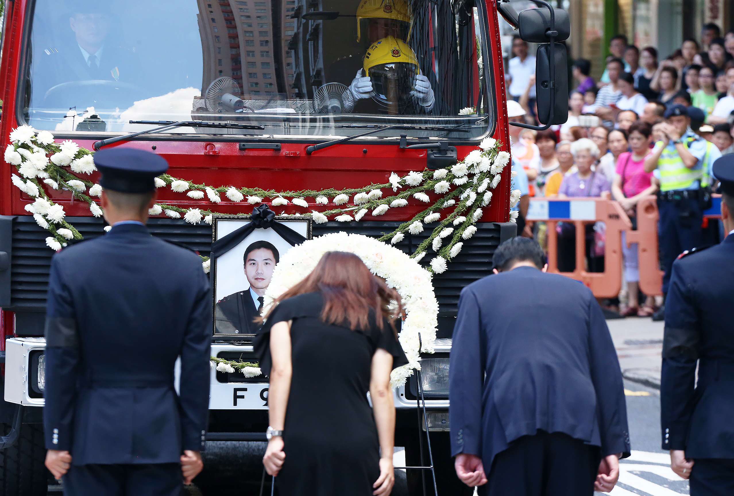 The funeral service for late fireman Samuel Hui went past the the scene of the fire at Amoycan Industrial Centre in Ngau Tau Kok. Photo: K. Y. Cheng