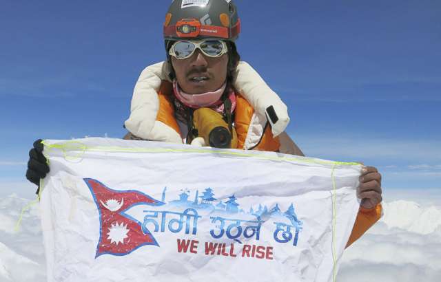 Phurba Tenzing Sherpa unfurls the flag of the We Will Rise foundation at the summit of Mount Everest in May 2016. Photo: Phurba Tenzing Sherpa