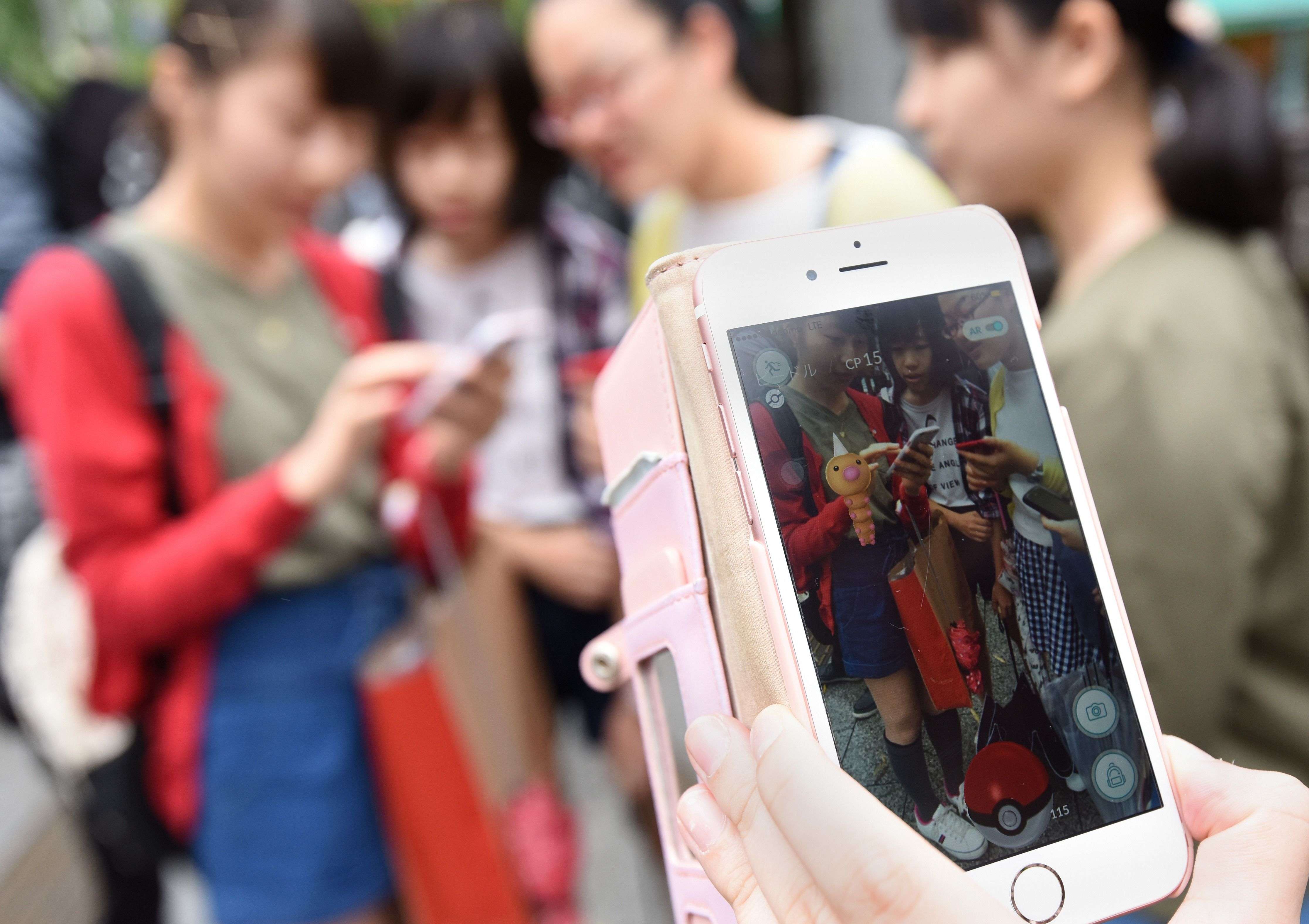 Schoolgirls play Pokemon Go on their mobile phones in Tokyo. Photo: AFP
