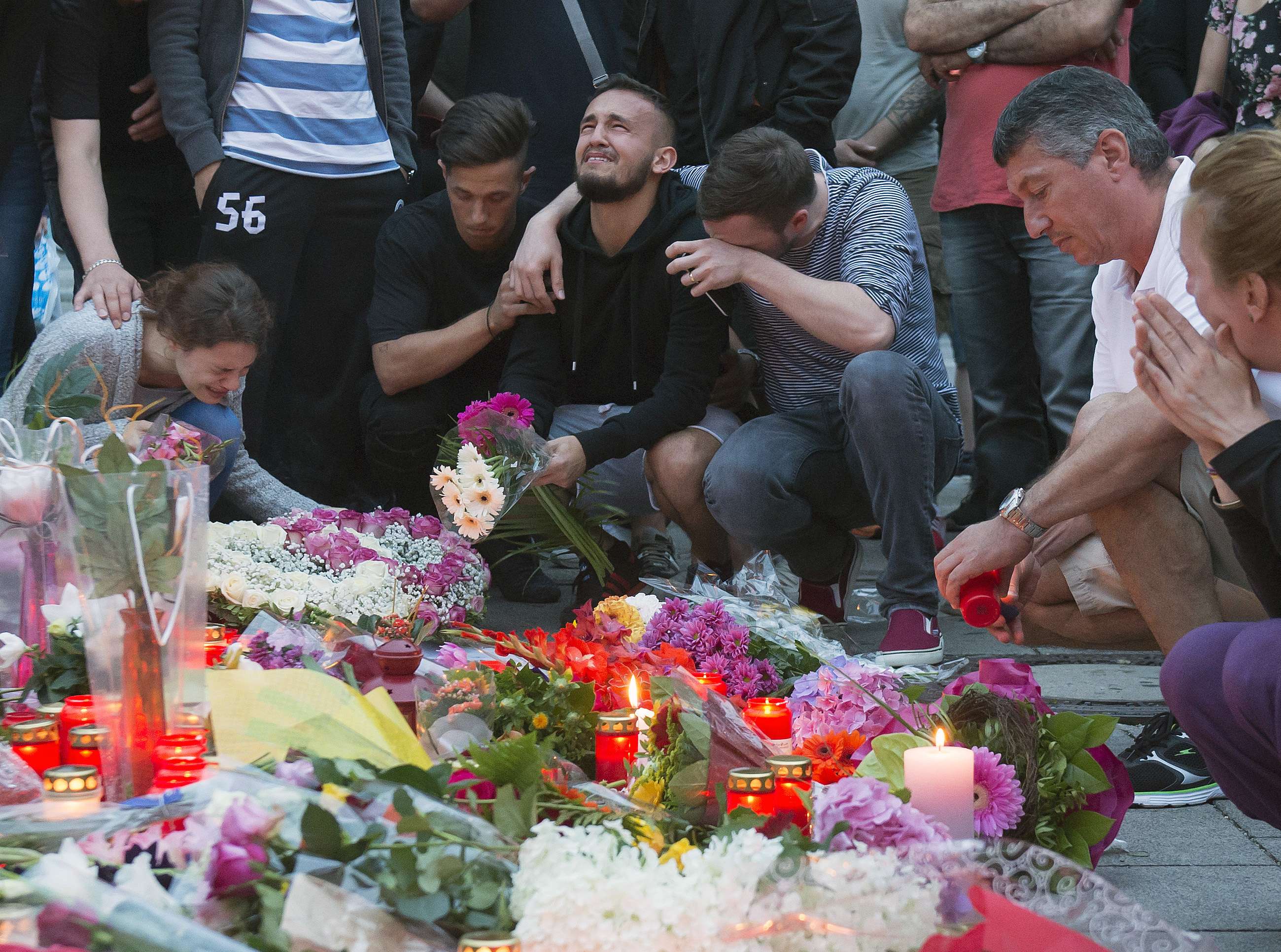 Tears flow as floral tributes are placed near the Olympia shopping centre in Munich where a lone gunman killed nine, including children, on July 22. Photo: AP