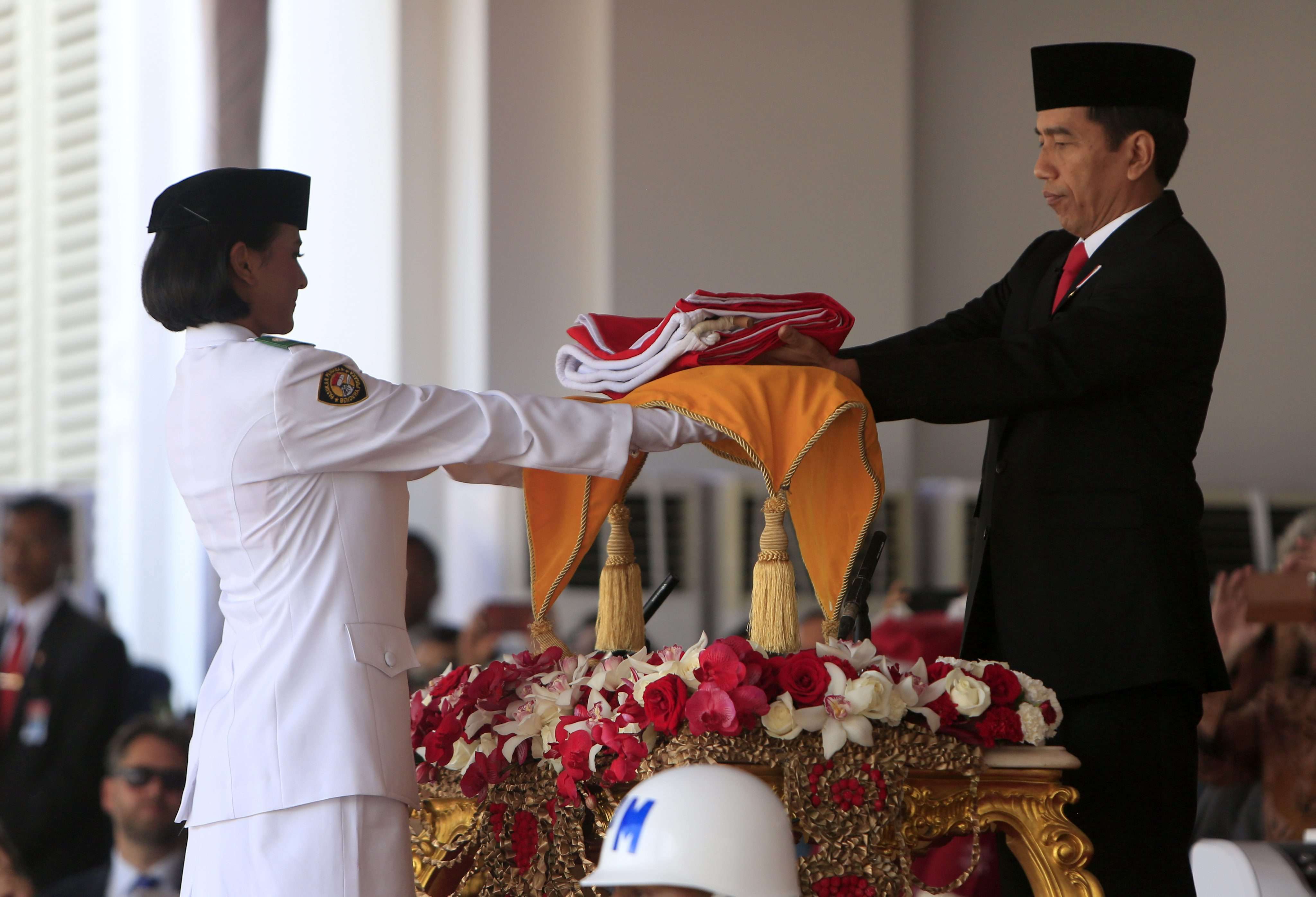 Indonesian President Joko Widodo (R) hands a folded national flag to a flag raiser during celebrations marking the 71th anniversary of Indonesia's independence day at the Presidential Palace in Jakarta. Photo: EPA