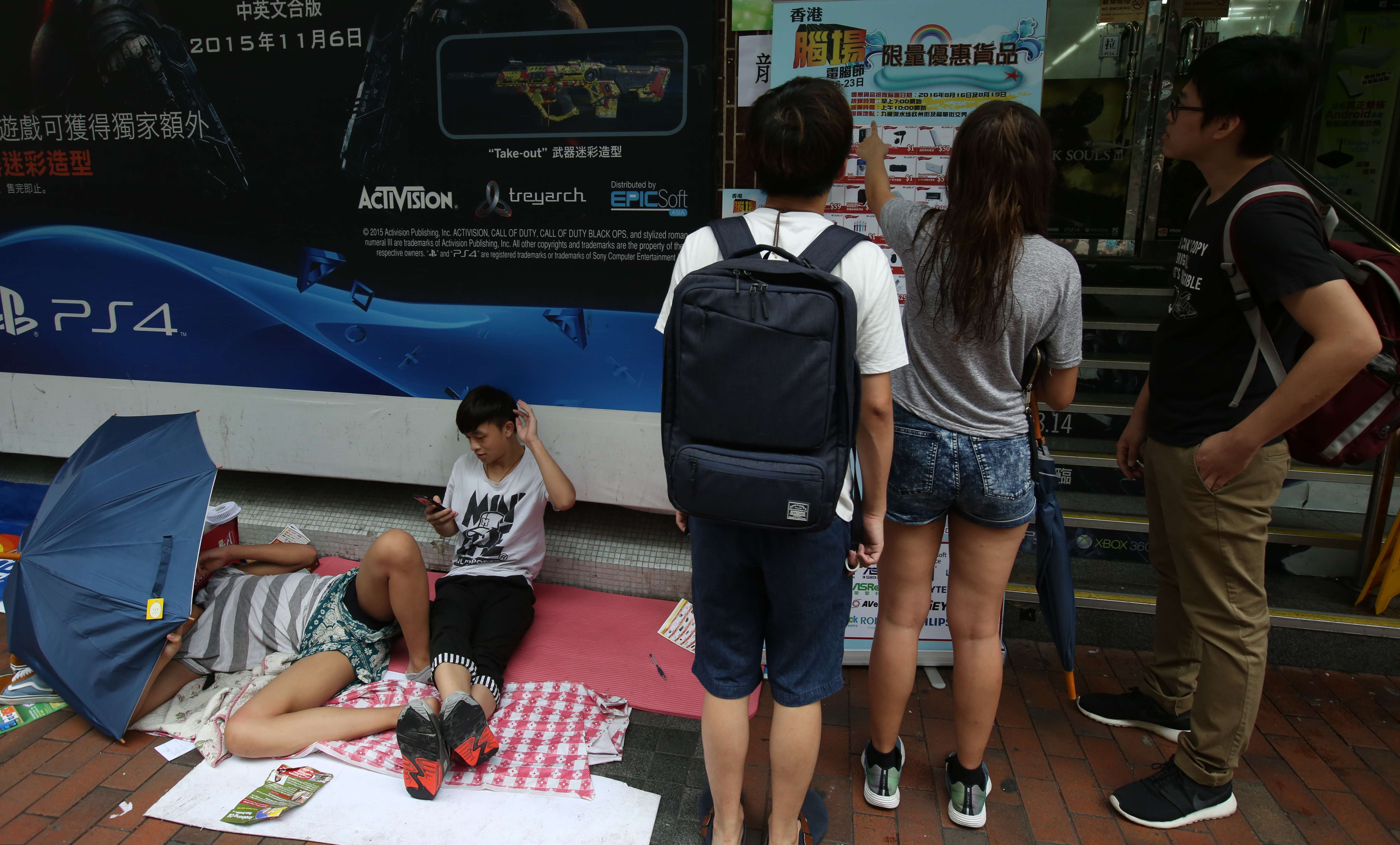 15-year-old Lee Ming (sitting) and his schoolmate have been queuing outside Golden Computer Arcade in Sham Shui Po since Sunday. Photo: Nora Tam