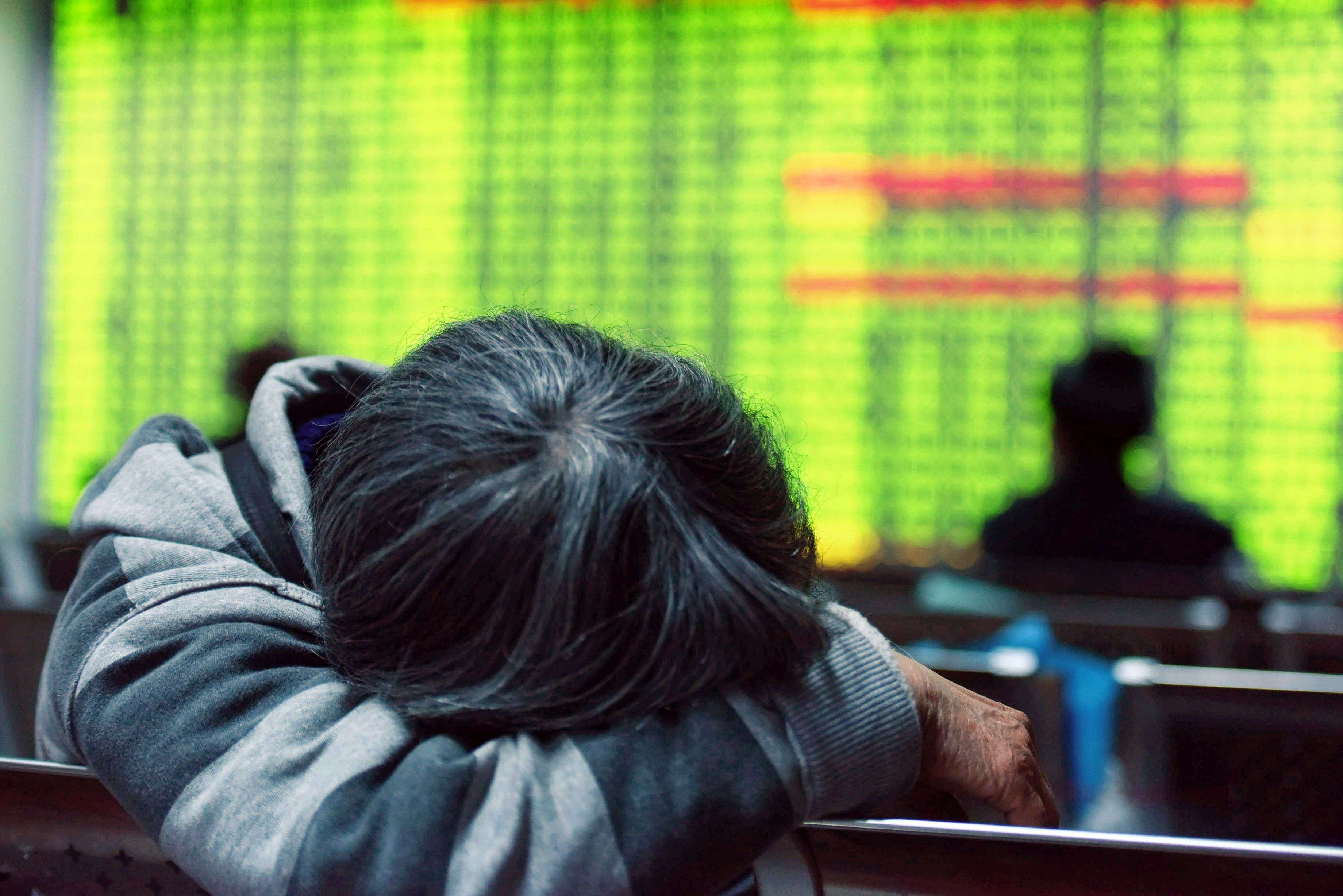 A weary investor after the Shanghai stock index tumbled 5 per cent on January 11. Opposite to global norms, green colour in China’s equity market indicates declines. Photo: AFP