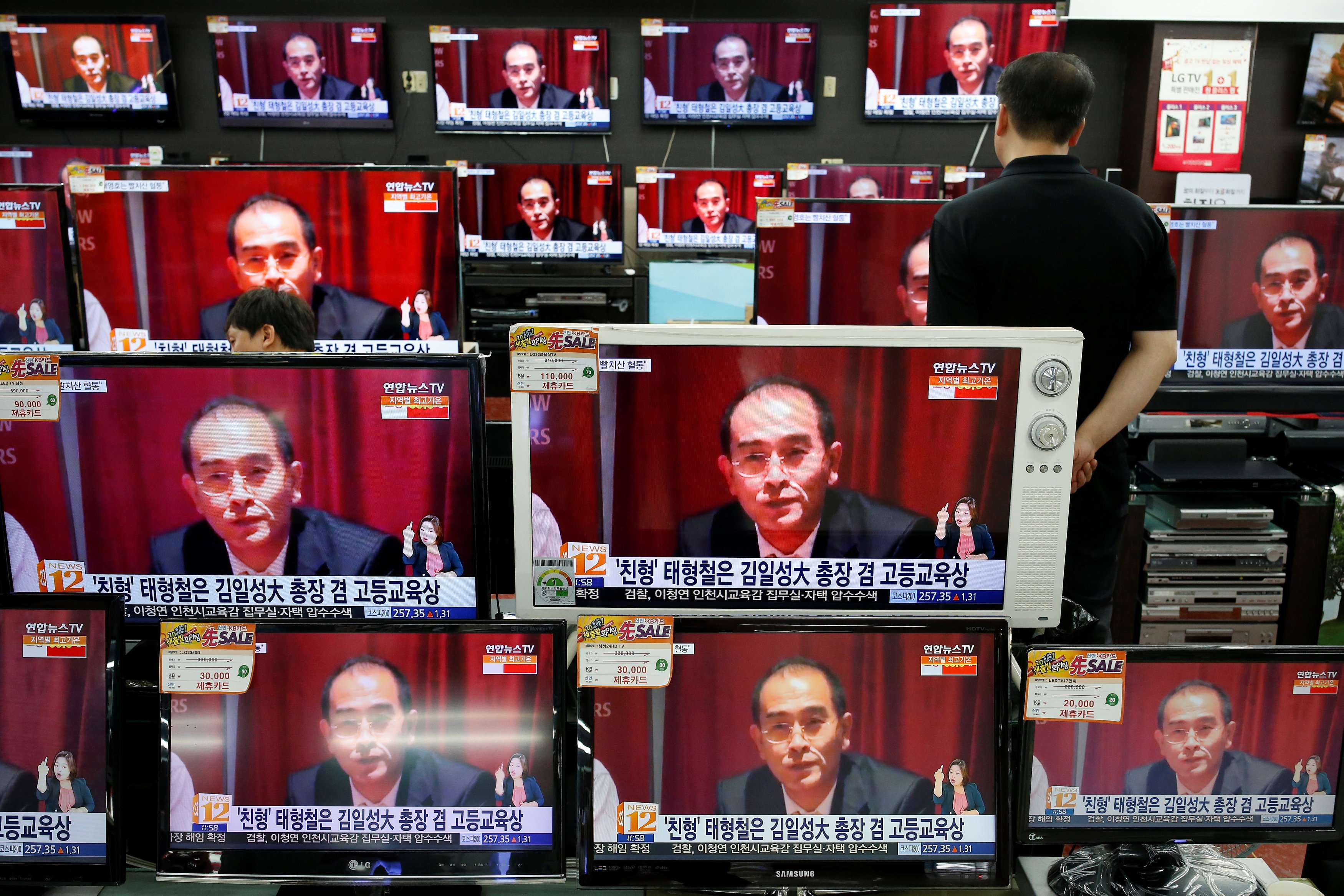 A sales assistant watches TV sets broadcasting a news report on Thae Yong Ho, North Korea's deputy ambassador in London, who has defected with his family to South Korea. Photo: Reuters