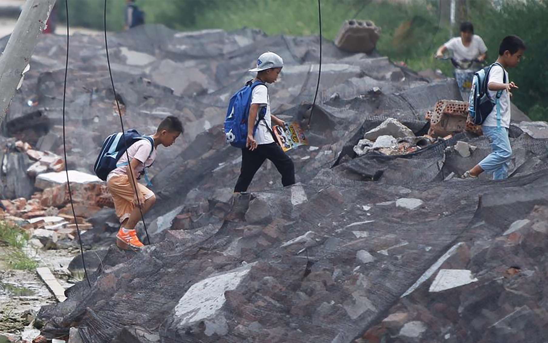 Children walk over the dumped waste on their way to classes. Photo: Qq.com