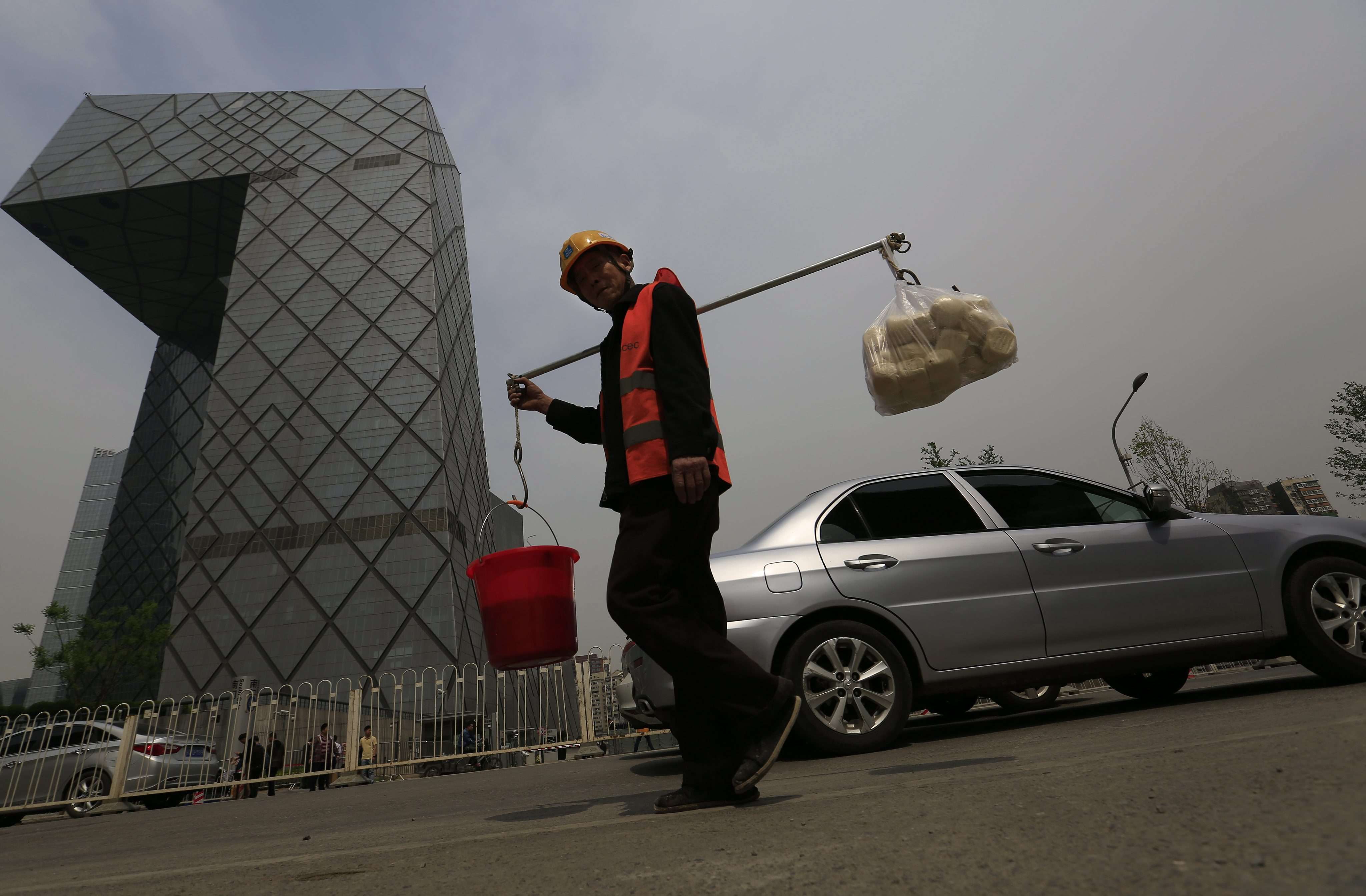 A construction worker carries supplies past Beijing’s iconic CCTV Tower. The Chinese economy advanced an annual 6.7 per cent in the second quarter, slightly above market expectations. Photo: EPA
