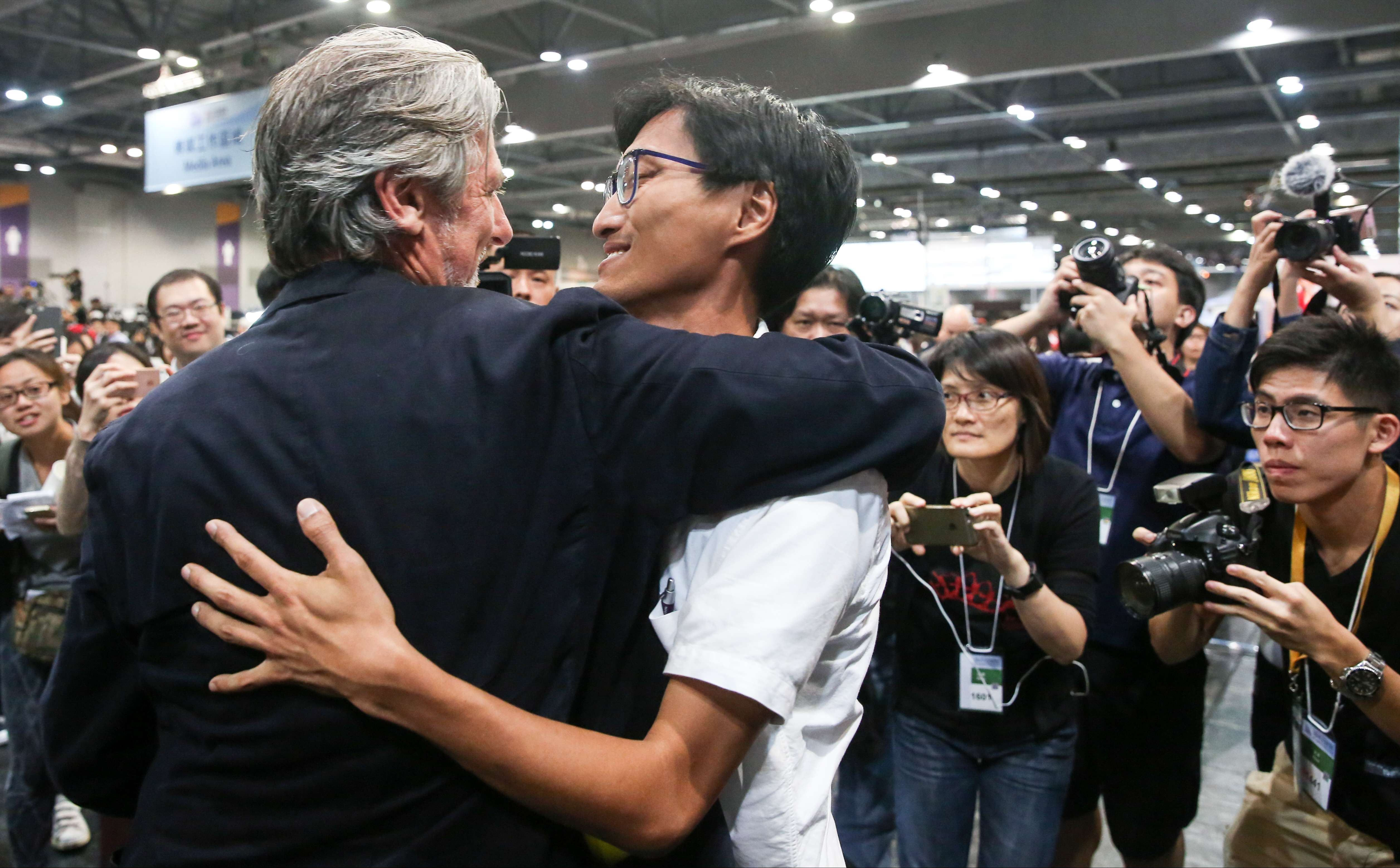 Paul Zimmerman, one of the five pan-democratic candidates who stopped campaigning two days before the election, hugs Eddie Chu Hoi-dick after he won a seat in New Territories West. Photo: Sam Tsang