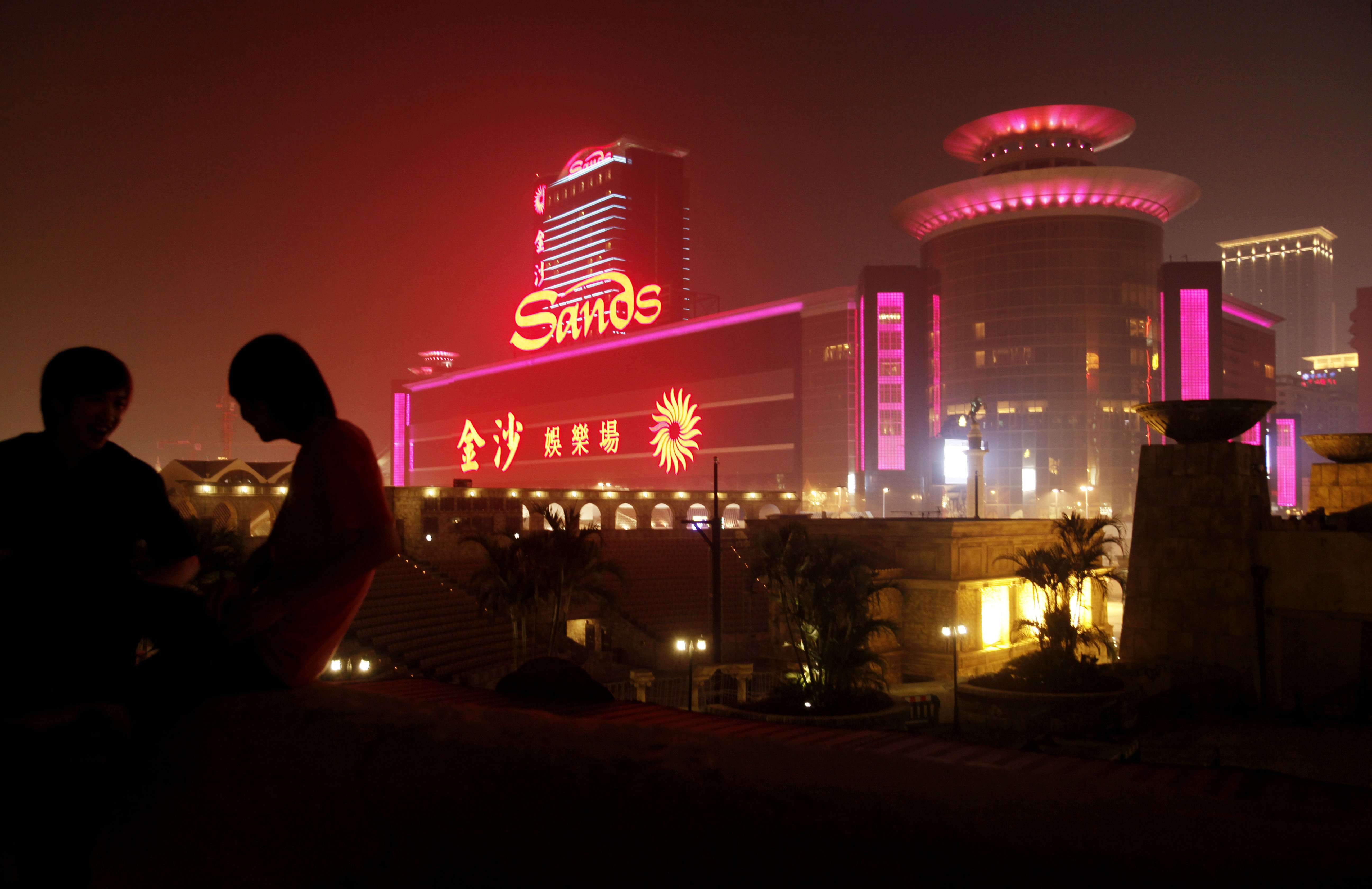 Two men sit in front of the Sands Casino in Macau. Photo: AP