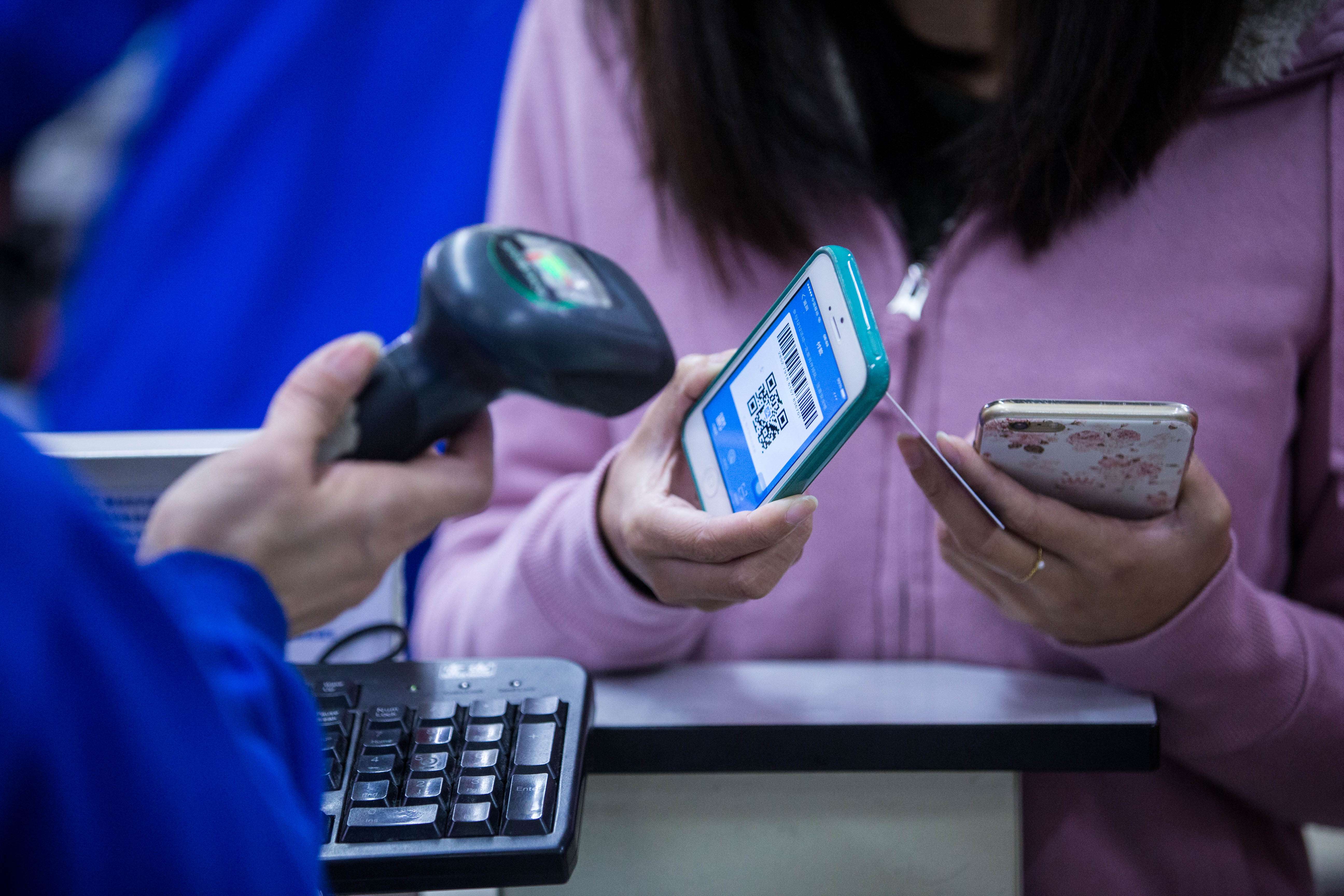 A Chinese customer has a barcode on her Apple iPhone smartphone scanned by a cashier for payment through Alipay of Alibaba's Ant Financial at a supermarket in Hangzhou city, east China's Zhejiang province. File photo