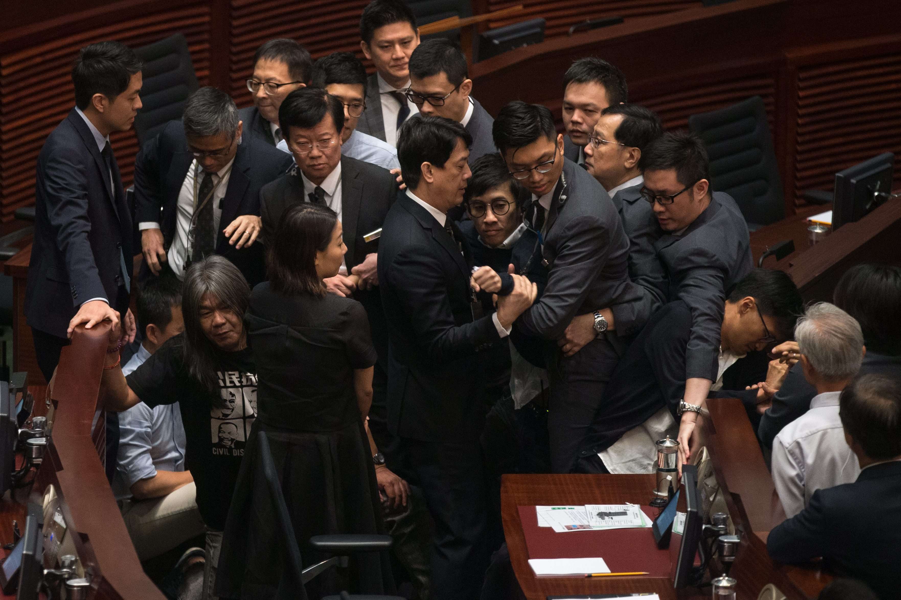 Security guards try to remove legislator-elect Sixtus Leung (centre) from the Legislative Council chamber as pan-democrats create a protective ring around him on November 2. The chaos in the aftermath of the oaths controversy has caused much damage to Hong Kong society. Photo: EPA