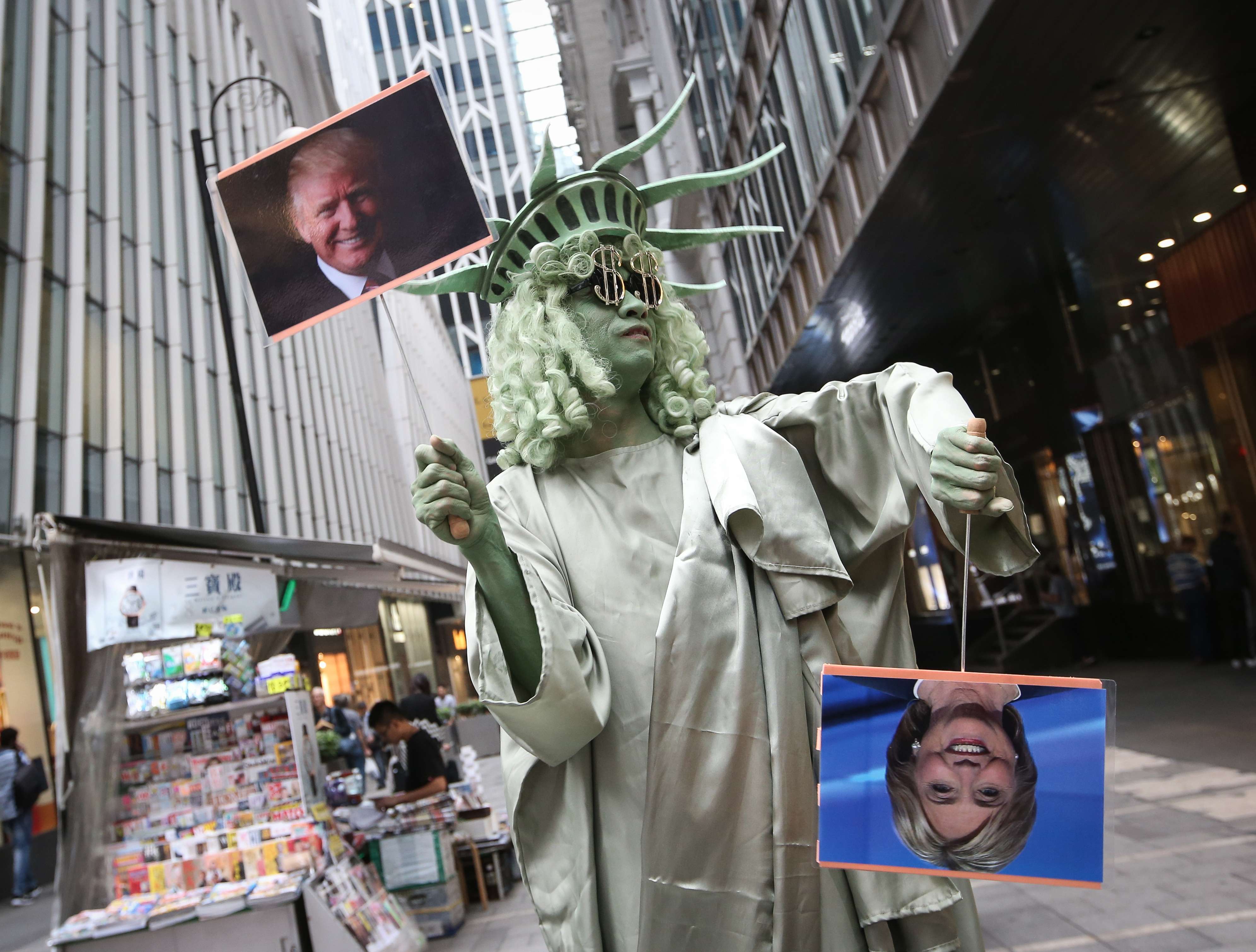 Andrew So, director of HK Funny Clown Theatre, dressed as the Statue of Liberty, holds photos of Donald Trump and Hillary Clinton in downtown Hong Kong on Wednesday. Many observers expect some major changes to US foreign policy ­towards Asia during Trump’s presidency. Photo: David Wong