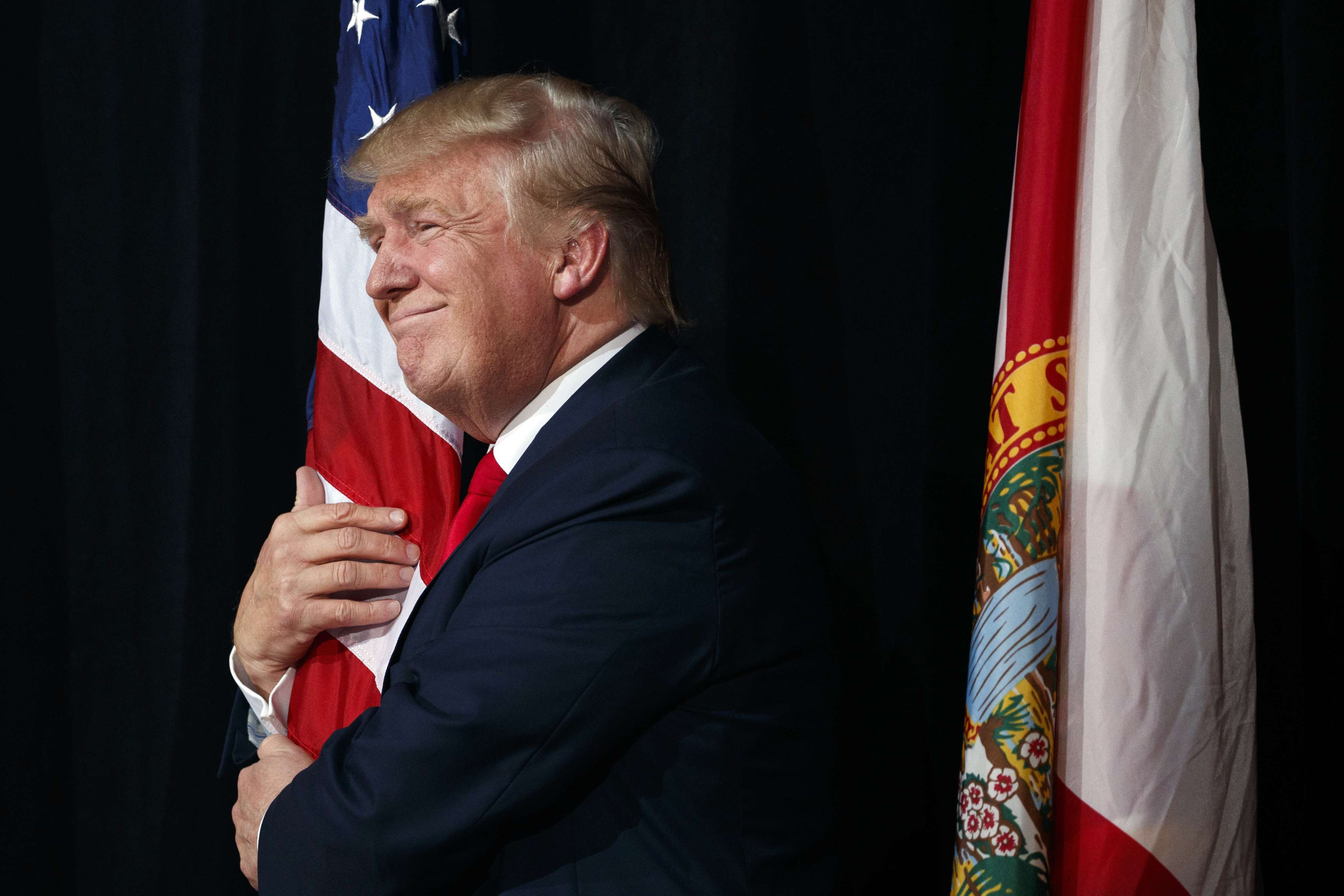 Republican presidential candidate Donald Trump hugs a the American flag as he arrives to speak to a campaign rally last month in Tampa, Florida. Photo: AP