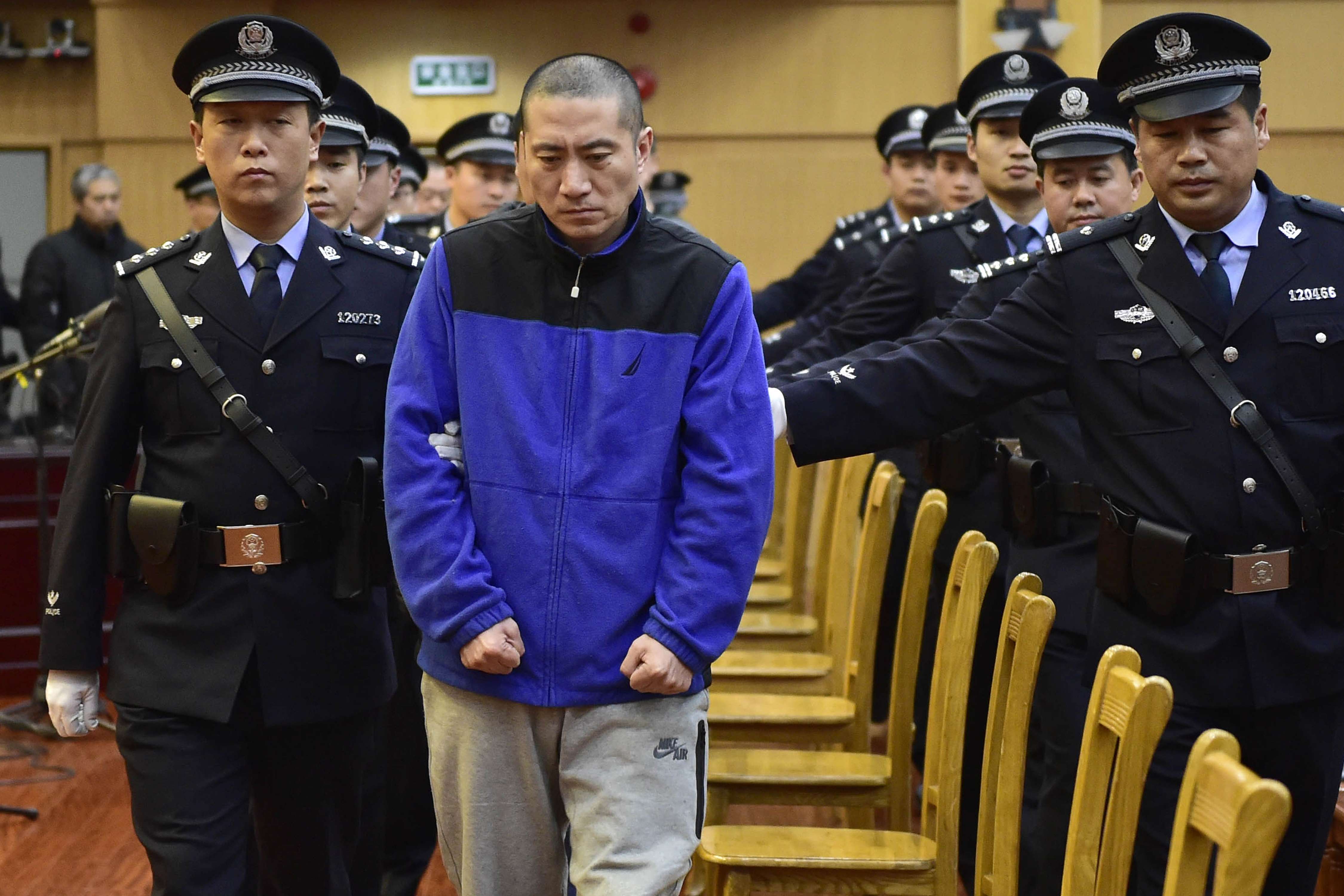 Yu Xuewei (centre), chairman of Ruihai International Logistics, is led into court by police officers at the start of his trial in Tianjin on Wednesday. Photo: Xinhua