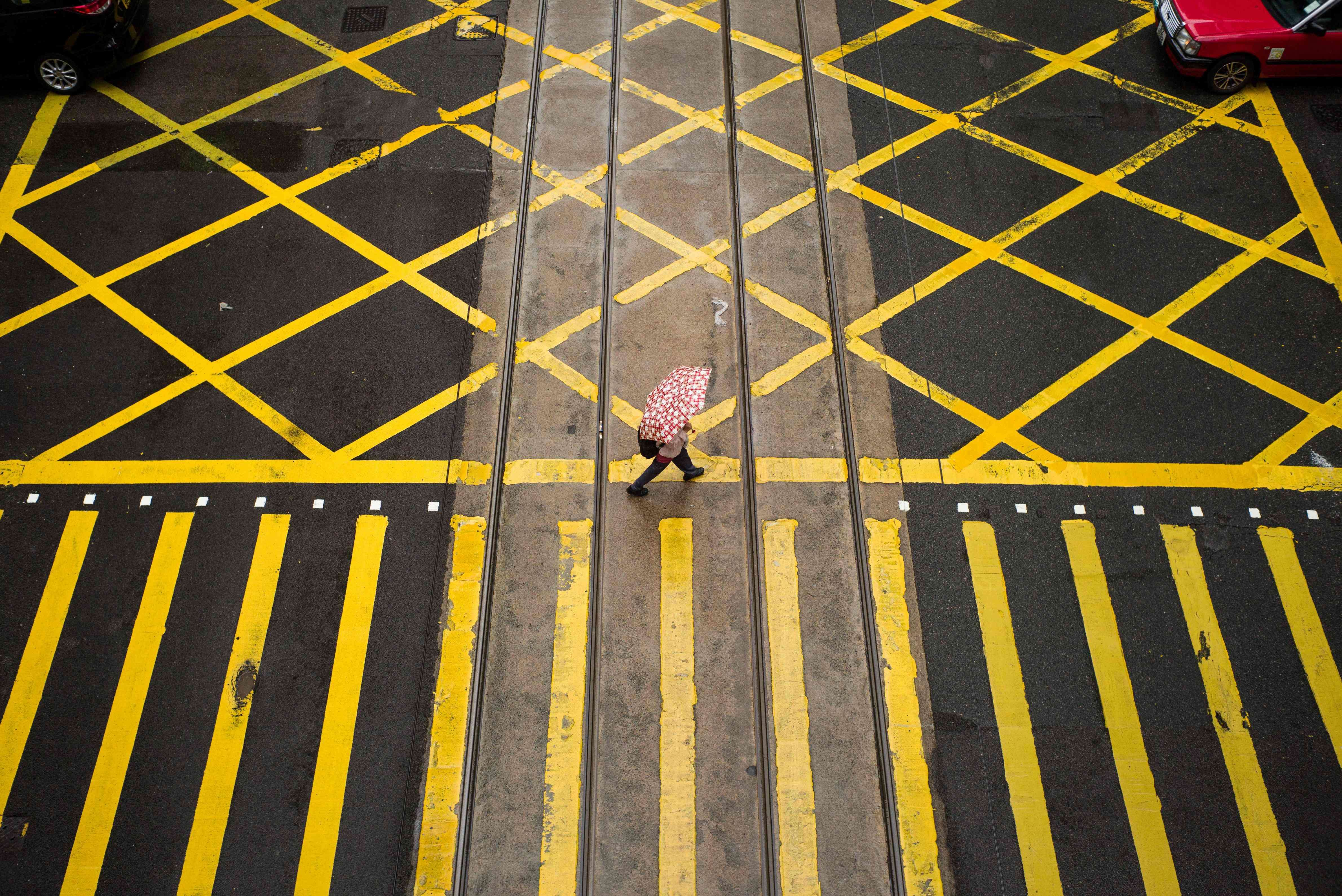 A pedestrian crosses a road in Hong Kong. Hong Kong’s economy is unapologetically capitalist, while the mainland is a socialist state. The assumption that the mainland will eventually become capitalist and converge with our economy is too simplistic. Photo: AFP