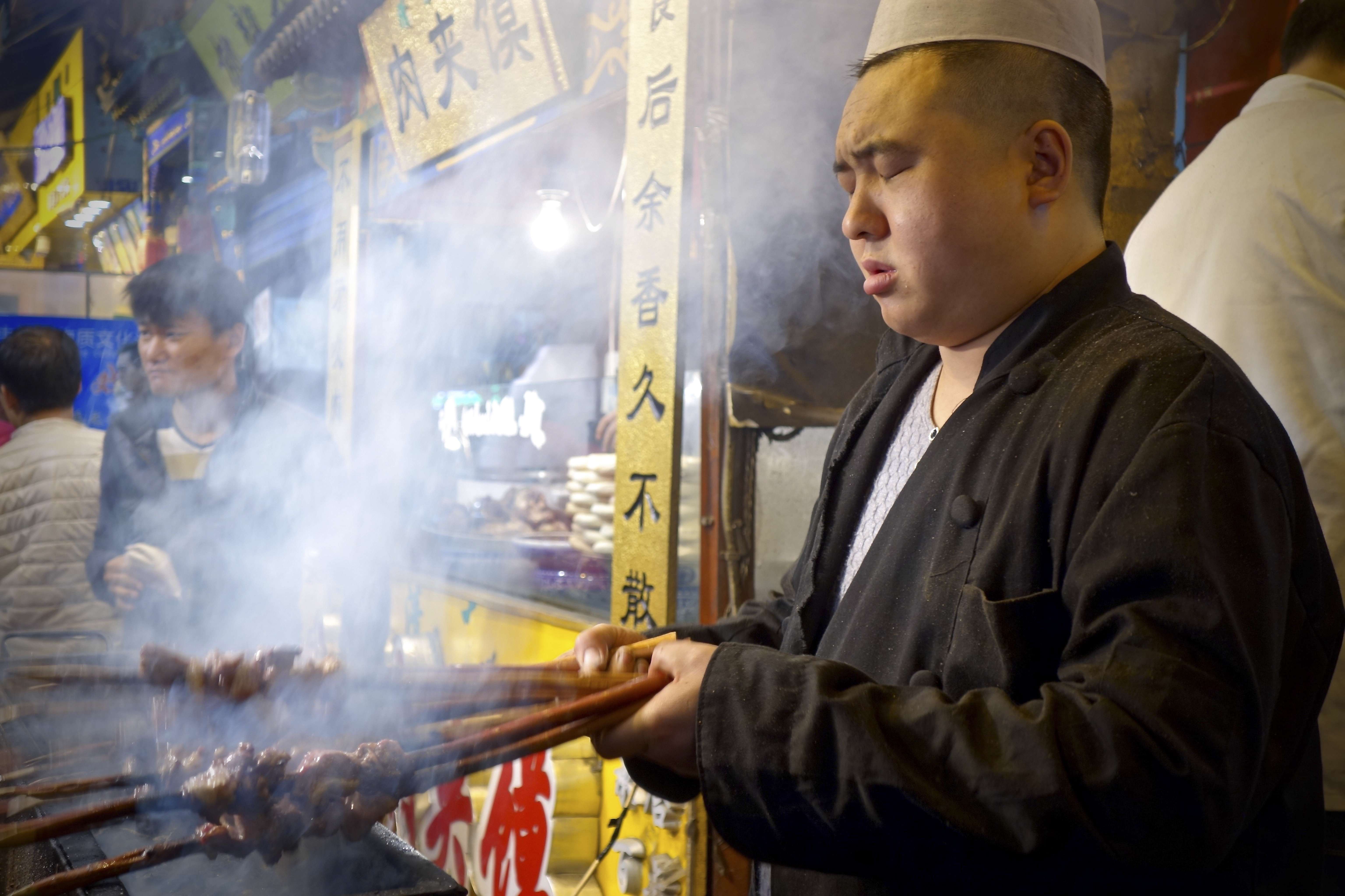 A cook at work with barbecuing skewers in Xian. Photos: Juli Min