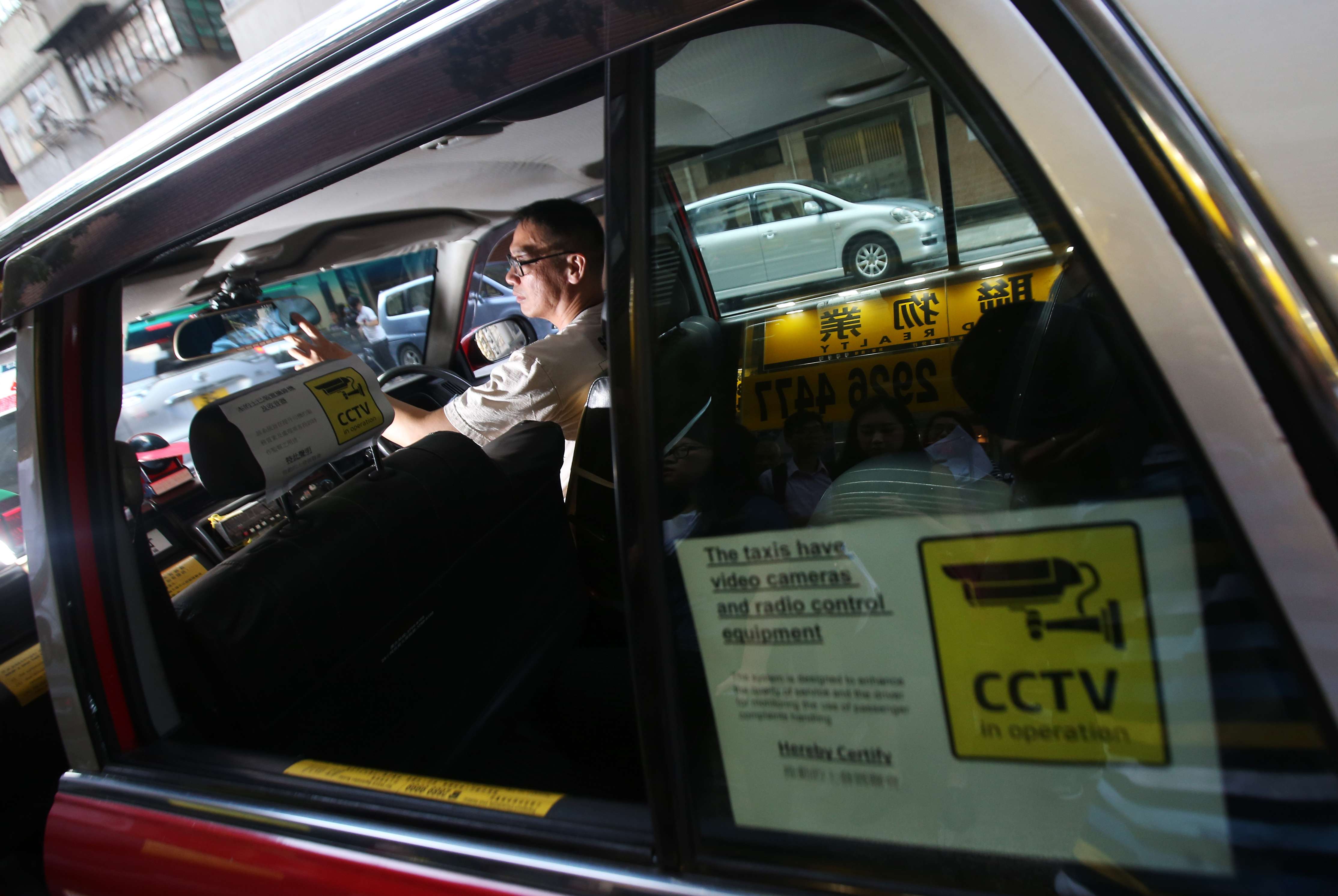 A rear window sticker declares the presence of closed-circuit TV cameras and radio equipment in a taxi in Ho Man Tin last September. The Association of Taxi Industry Development says it aims to raise service quality with the installation of on-board surveillance cameras. Photo: David Wong