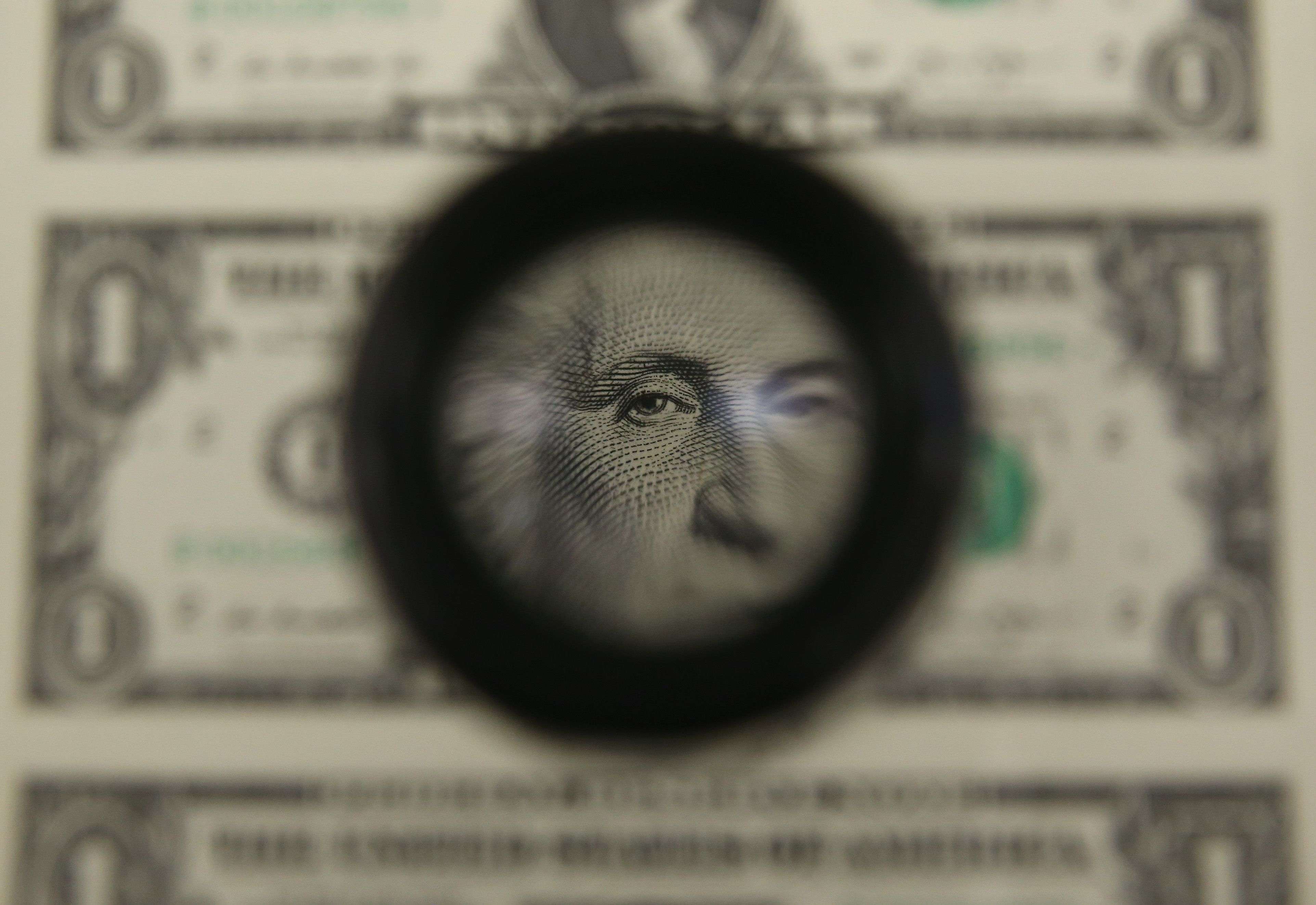A magnifying glass is used to inspect newly printed one dollar bills at the Bureau of Engraving and Printing in March 2015 in Washington, DC. Photo: Getty Images.