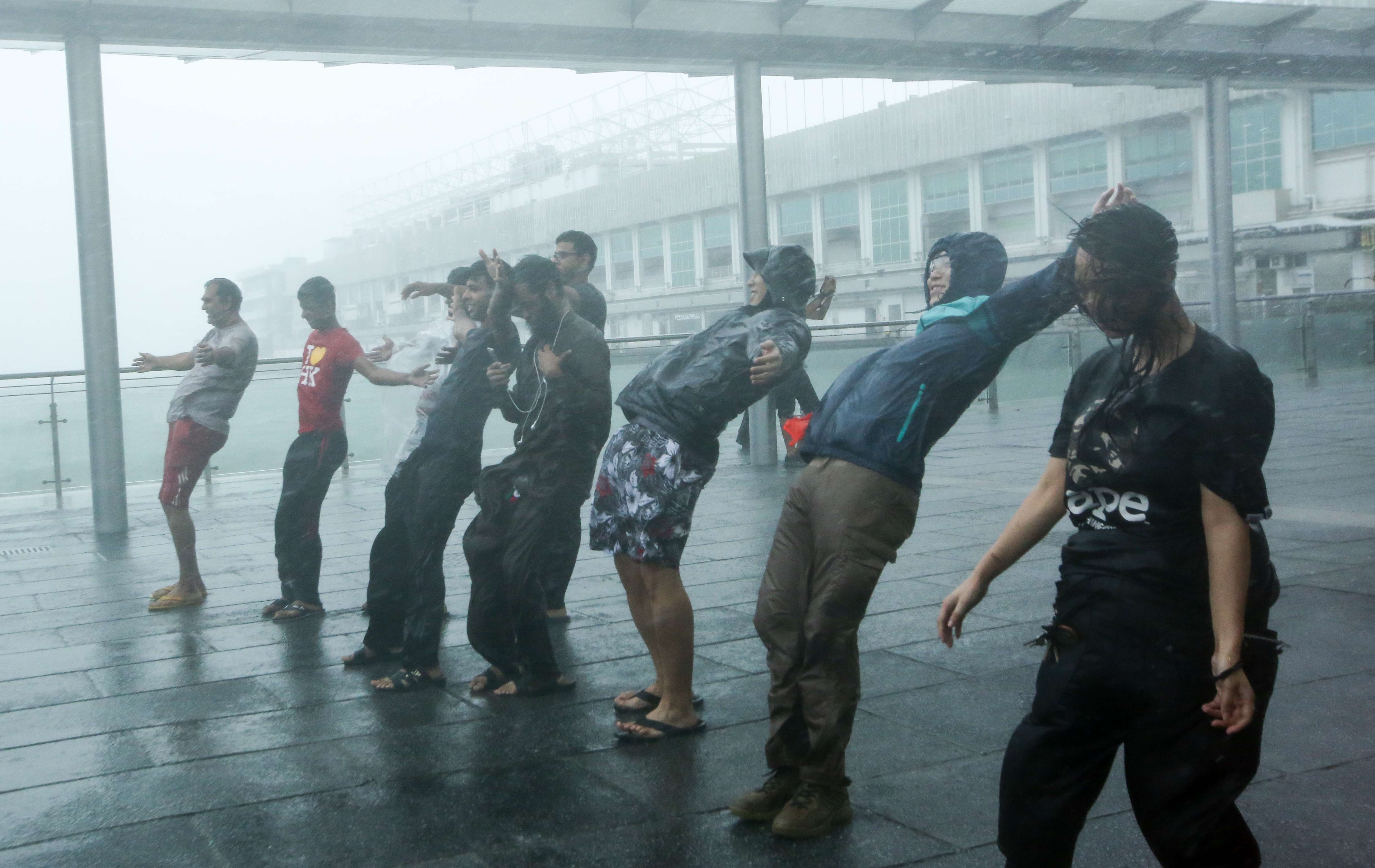 People brave the strong winds in Tsim Sha Tsui last October as Typhoon Haima hits Hong Kong. The consequences of global warming are not limited to extreme weather conditions or the increasing frequency and intensity of heat waves and cold spells that the media tends to focus on. Photo: Edmond So