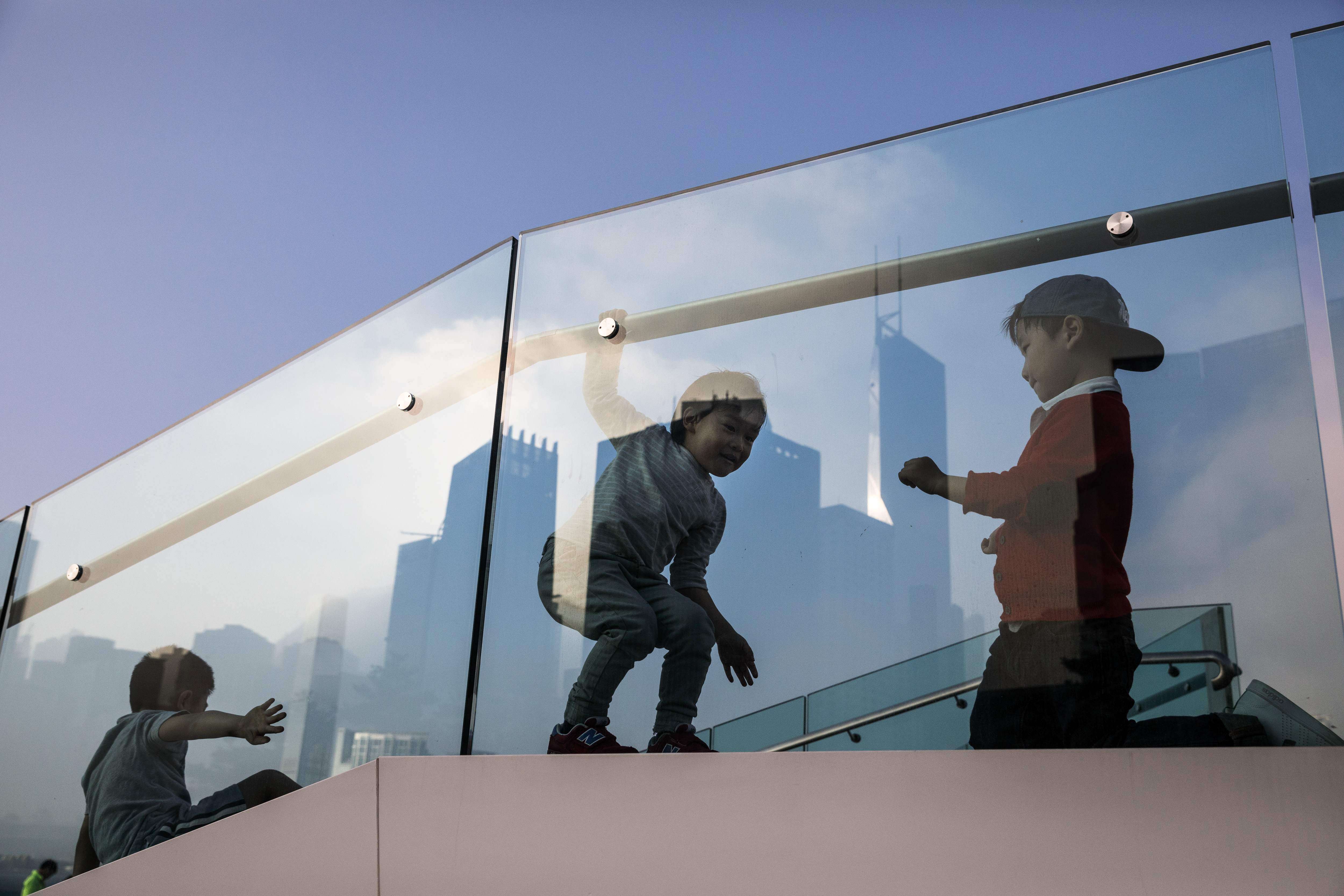 Children play on a viewing platform in Hong Kong as the city’s skyline is reflected in the glass panels. Hong Kong has long been a centre for processing questionable money flows. As a major financial player, it is under pressure to be truly compliant with global governance norms. Photo: AFP