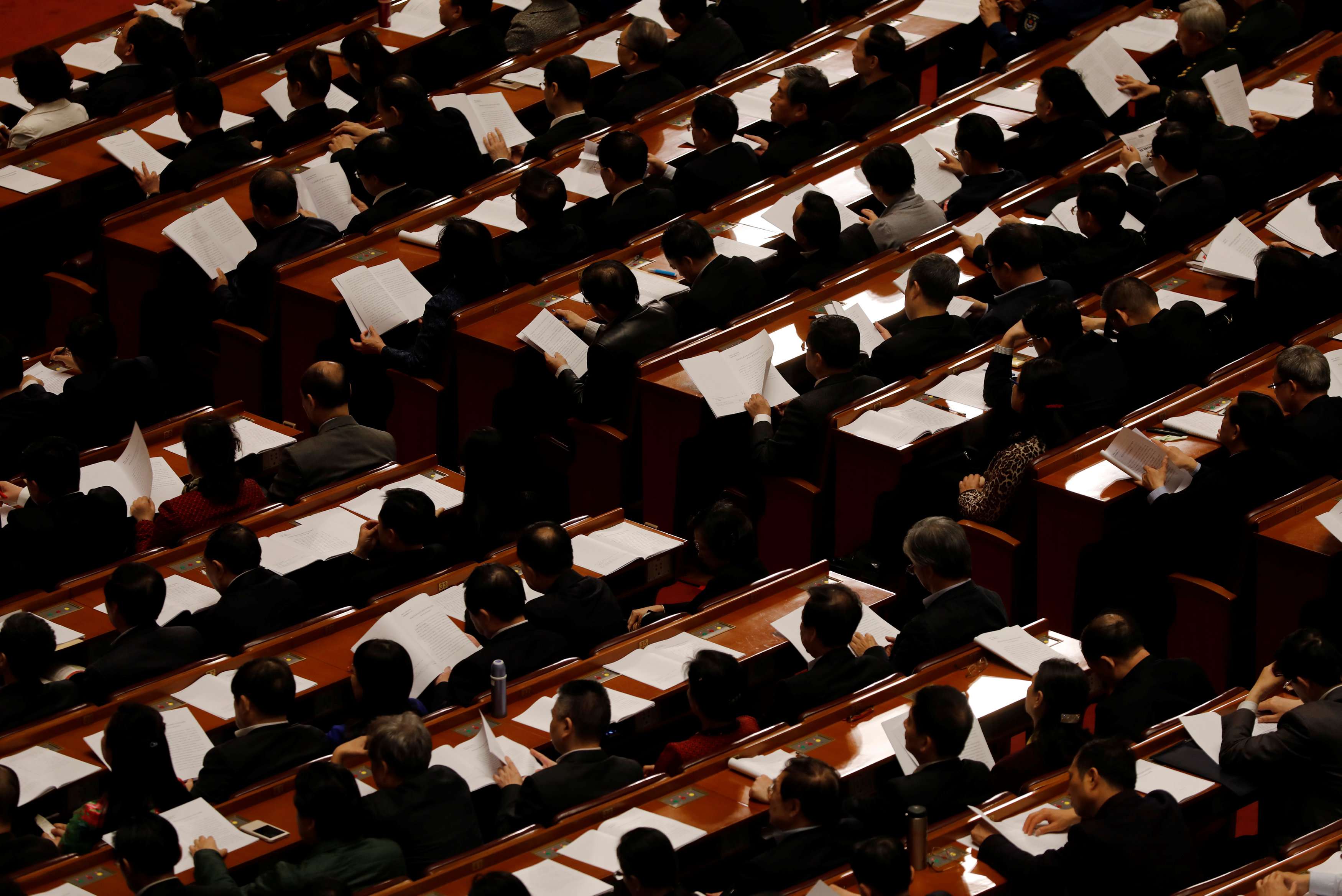 Delegates read papers at the Great Hall of the People in Beijing on Friday. Photo: Reuters