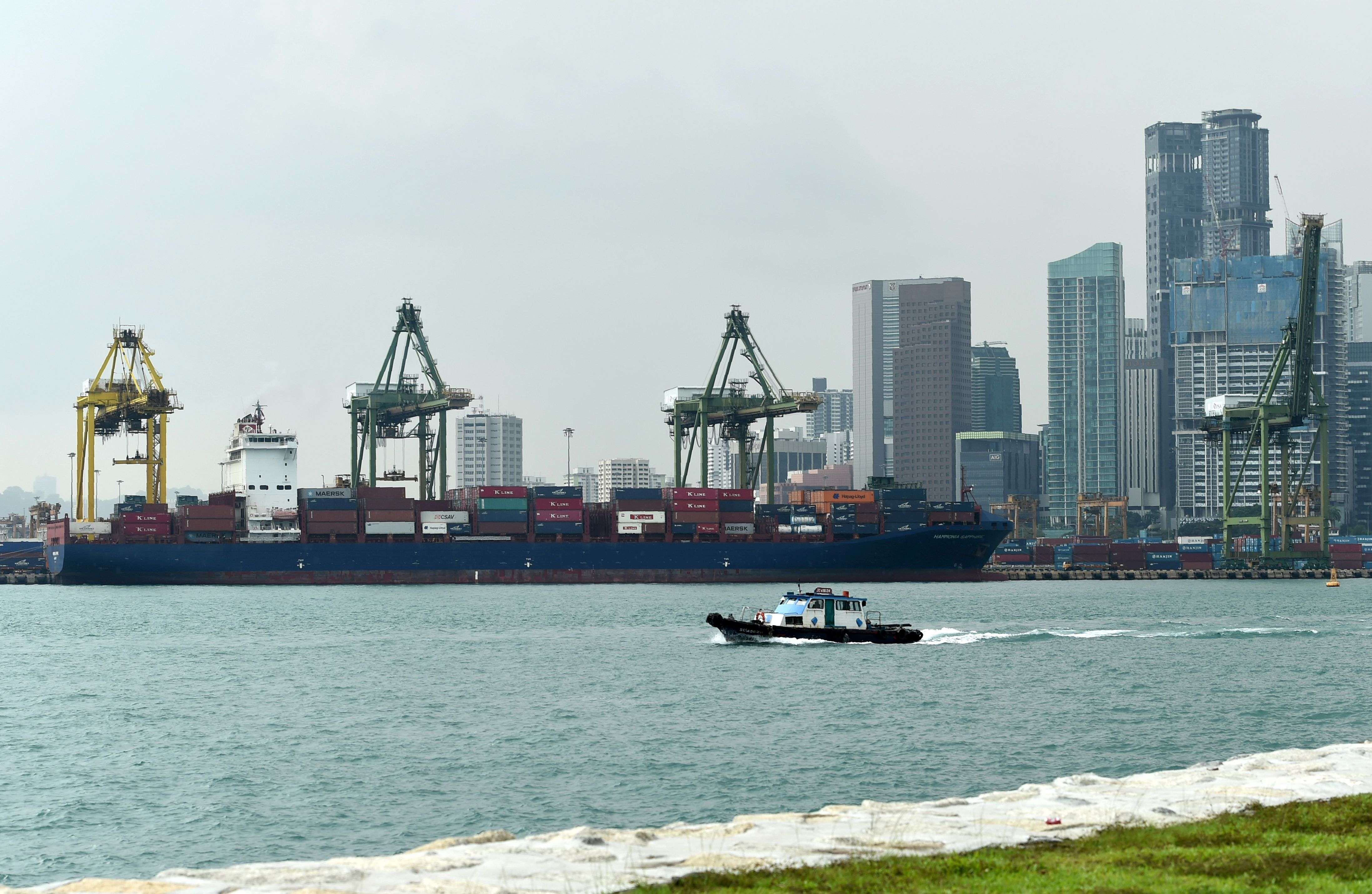 A boat leaving the pier passes Tanjong Pagar container terminal in Singapore on November 17. The city state is keen to compete for a leading position in regional maritime services, and Hong Kong must sharpen its edge. Photo: AFP