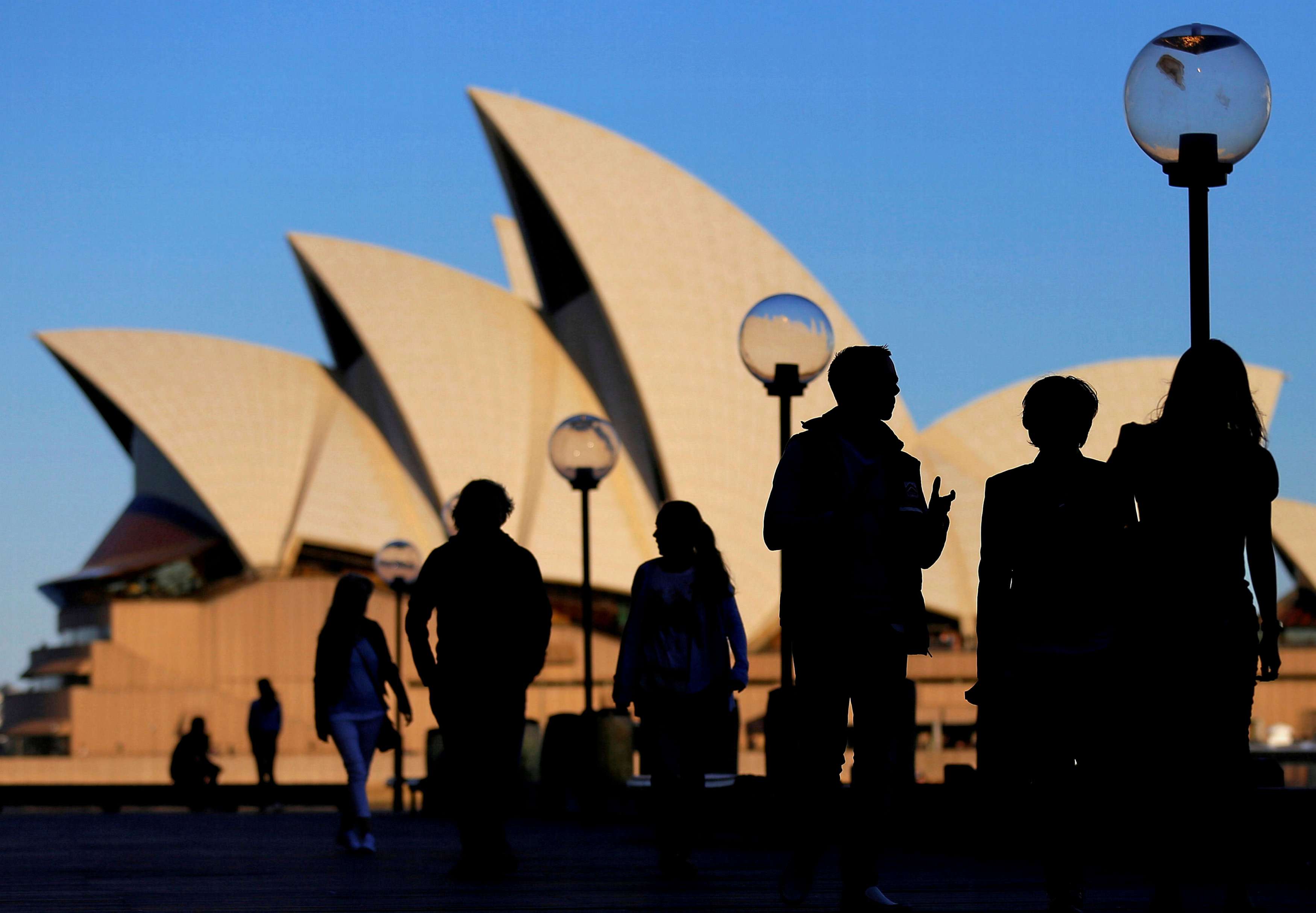 People are silhouetted against the Sydney Opera House at sunset in Australia. Australia has seen continuous growth since 1990, and the economy has greatly changed. The service sector comprises close to 80 per cent of GDP today, compared to around 60 per cent at the time of “Brentry”, while manufacturing employment has dropped from about 25 per cent to 10 per cent. Photo: Reuters