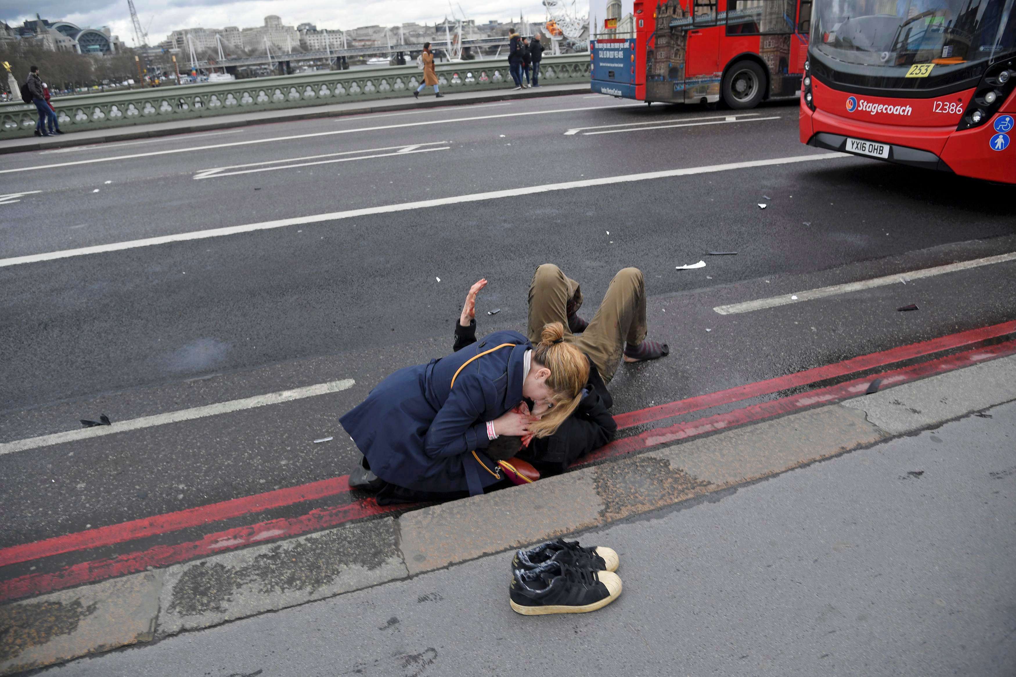 A woman assists an injured person after the attack on Westminster Bridge in London. Photo: Reuters