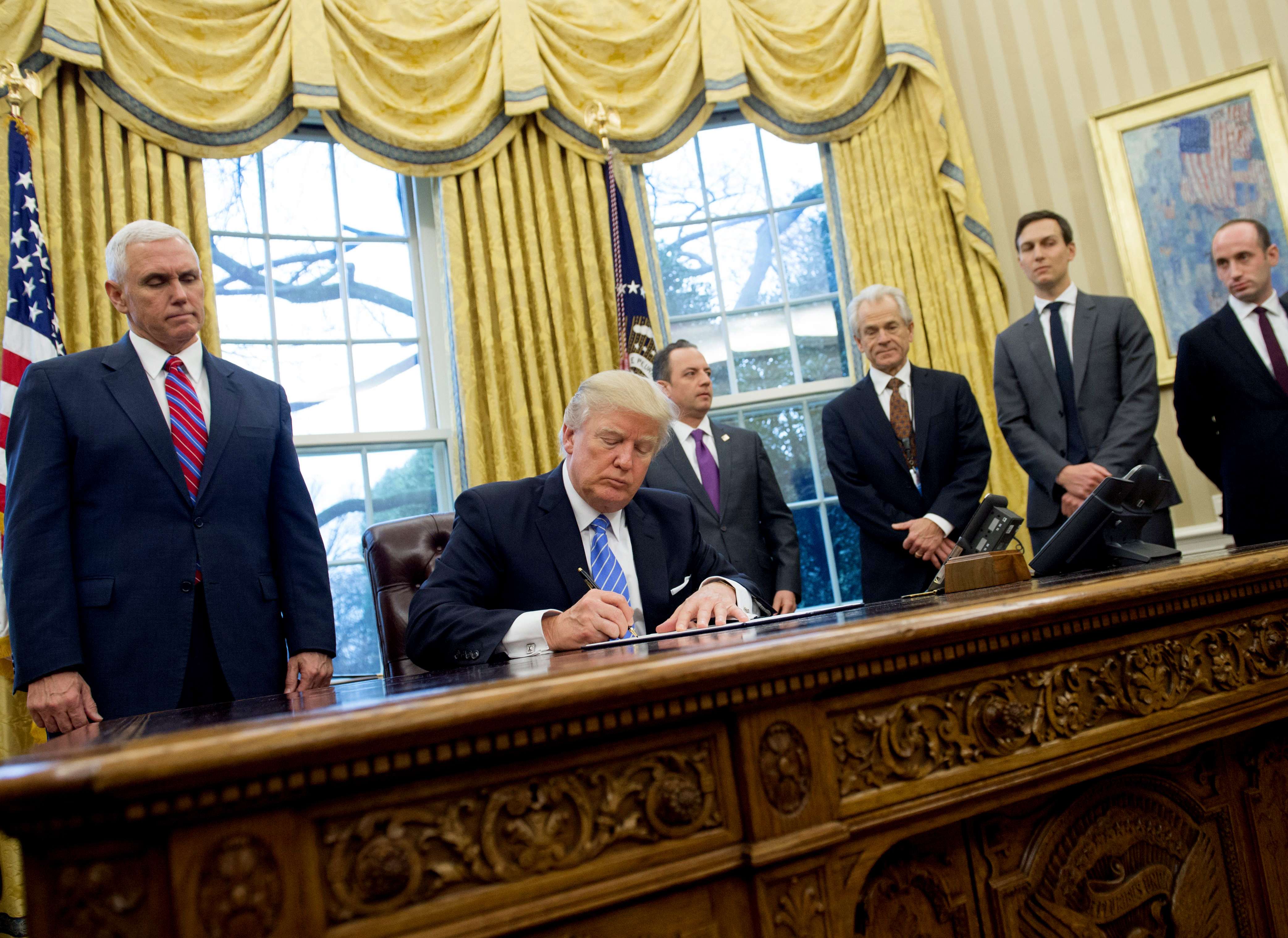US President Donald Trump signs an executive order watched by,standing, from left, Vice President Mike Pence, Chief of Staff Reince Priebus, National Trade Council Advisor Peter Navarro, Senior Advisor Jared Kushner and Senior Policy Advisor Stephen Miller in the Oval Office on January 23. Photo: AFP