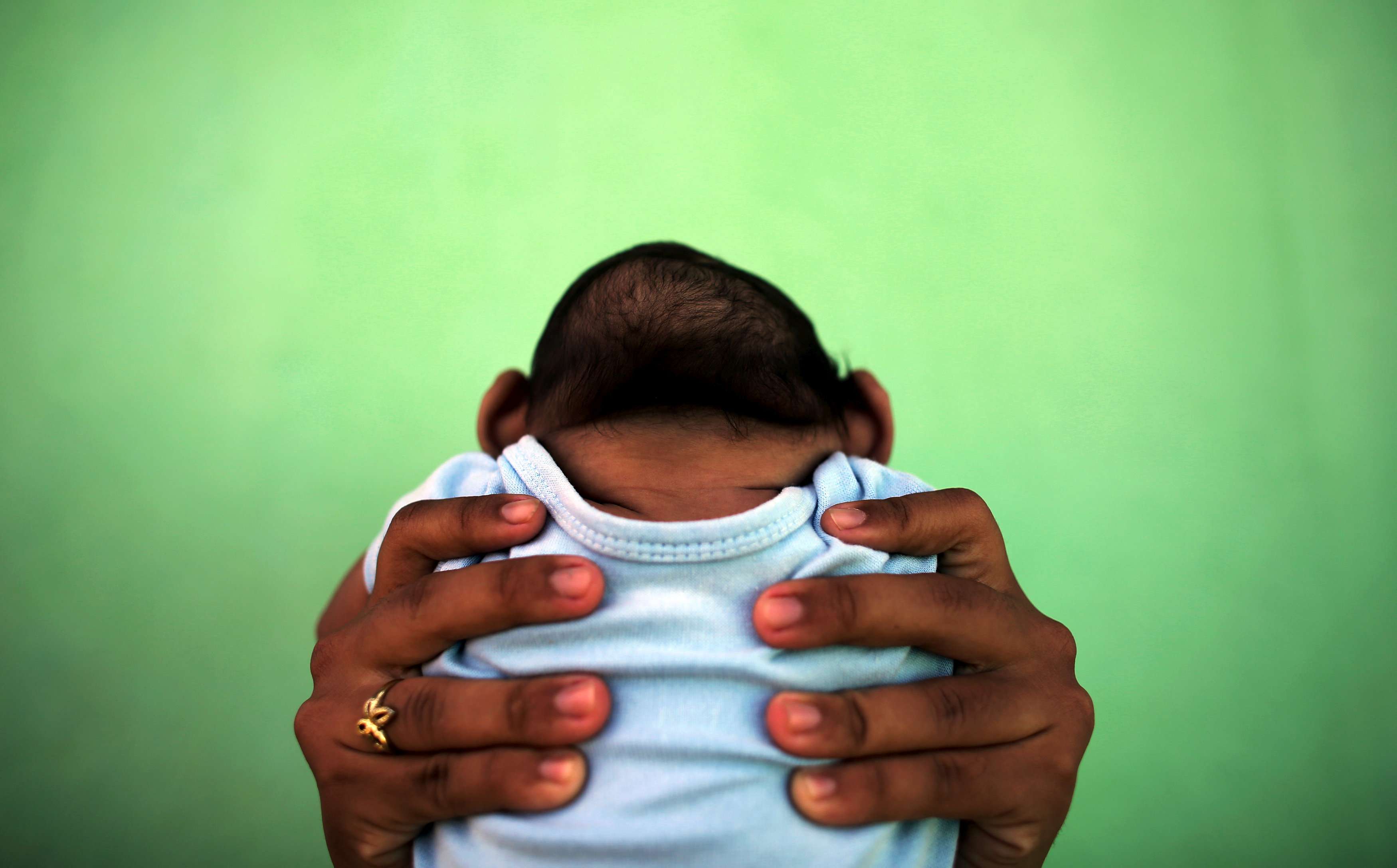 A mother holds her four-month-old son, born with microcephaly, in front of their house in Olinda, near Recife, Brazil. Photo: Reuters